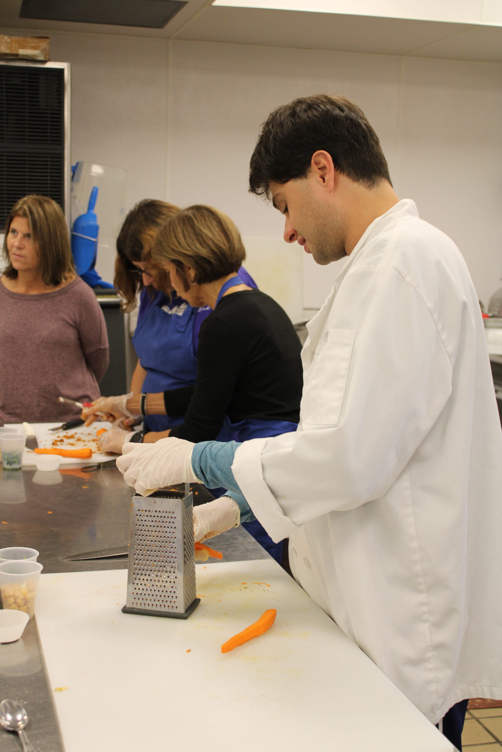 Christian Ciardiello grates carrots for a stuffed sweet potato recipe. Every Wednesday, the group meets to learn about kitchen safety, food handling and how to cook.   ELIZABETH VESPE