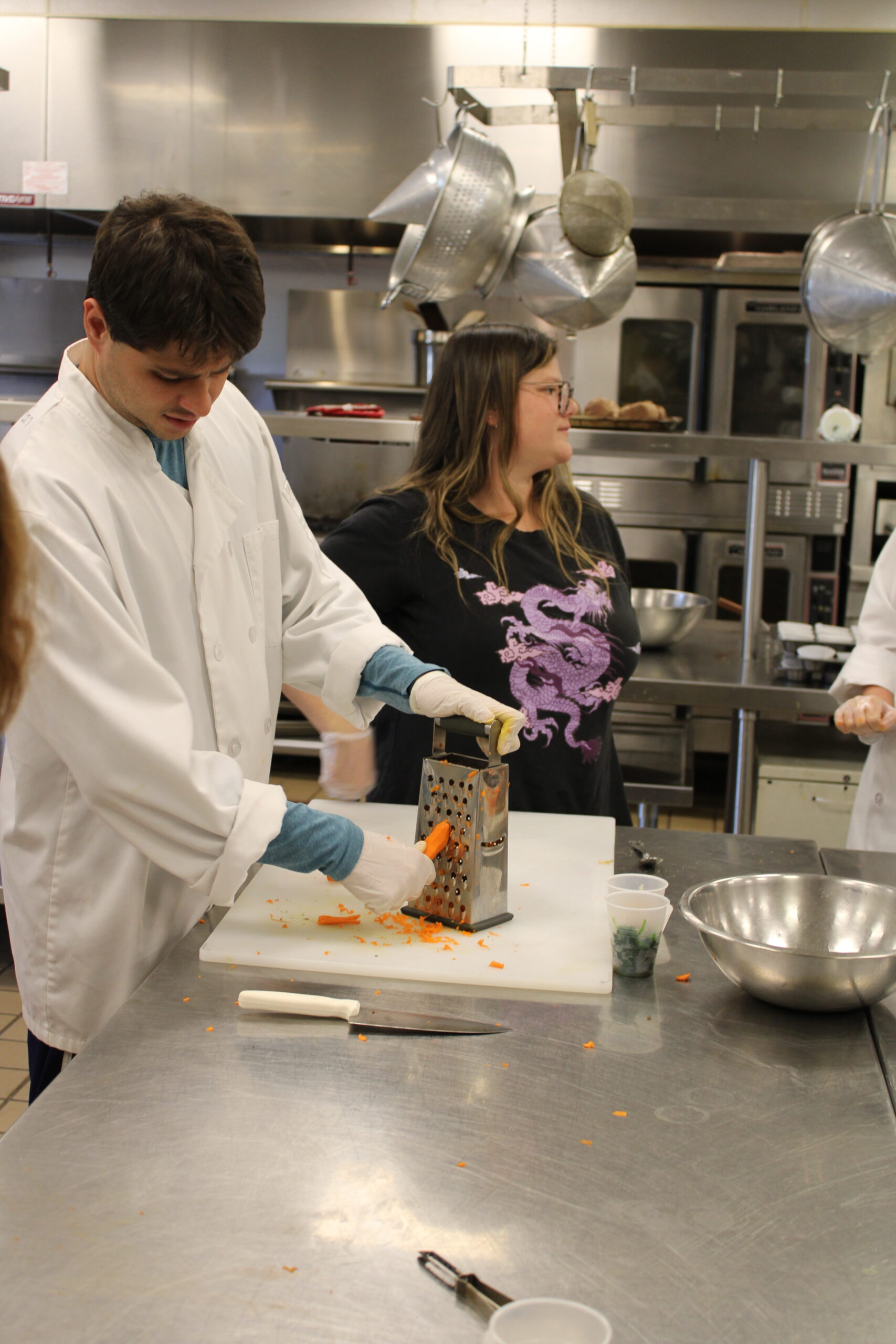 Christian Ciardiello grates carrots for a stuffed sweet potato recipe. Every Wednesday, the group meets to learn about kitchen safety, food handling and how to cook.  ELIZABETH VESPE