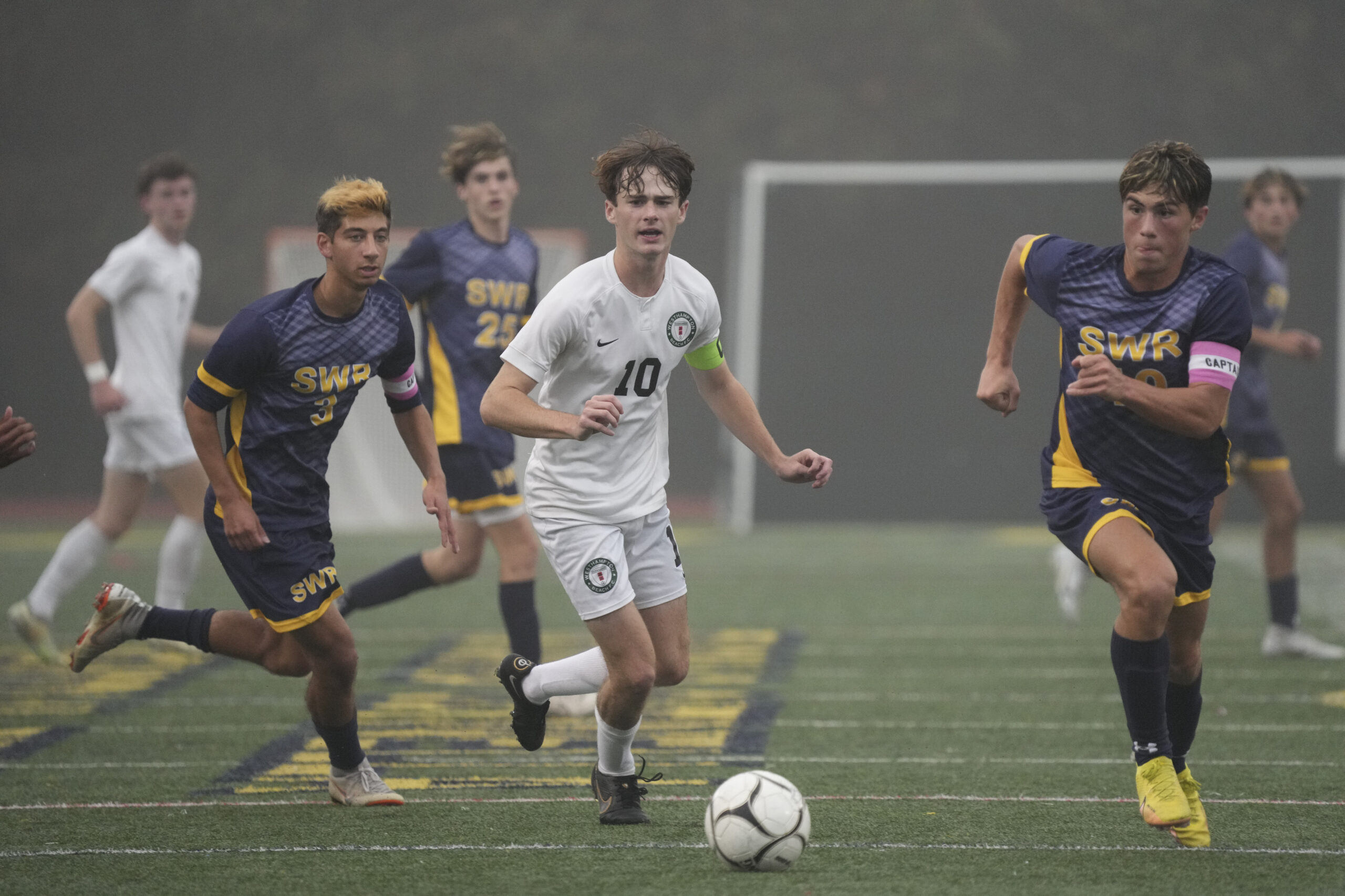 Westhampton Beach senior co-captain Kade Murphree works the ball between a pair of Shoreham-Wading River players.    RON ESPOSITO