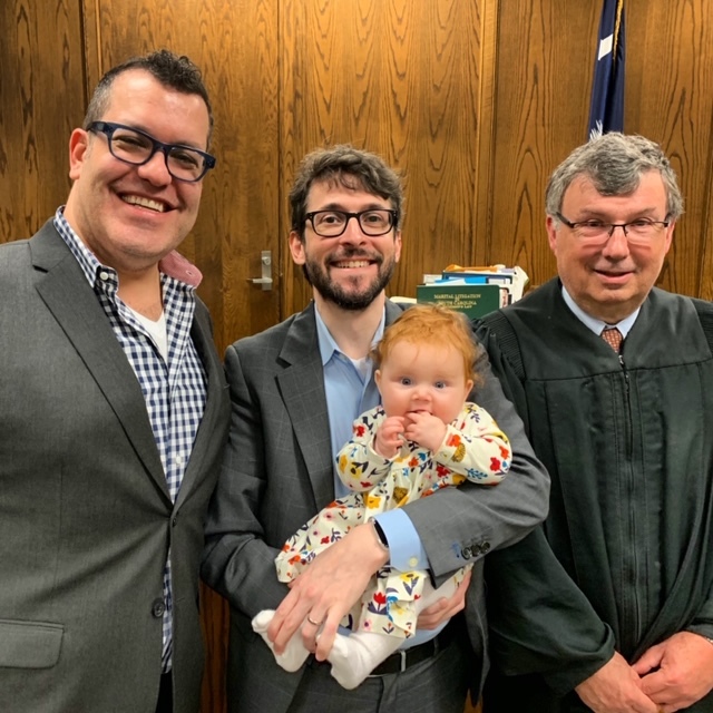 Eleanor with her parents, Christopher Michaud and Andrew Cohen, at their adoption finalization. COURTESY LORI KLING