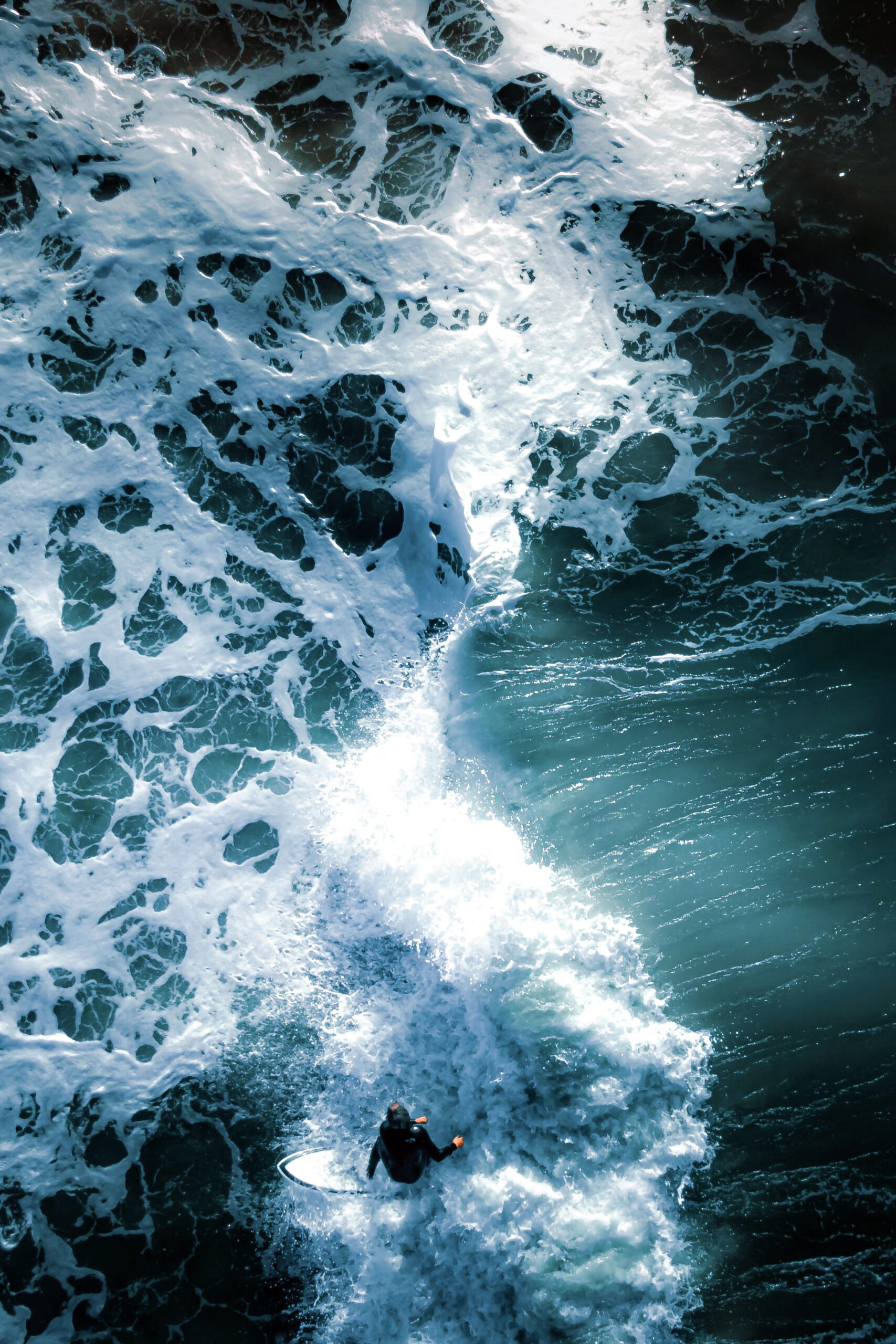 A surfer catches a wave in a drone photo by Joanna Steidle.