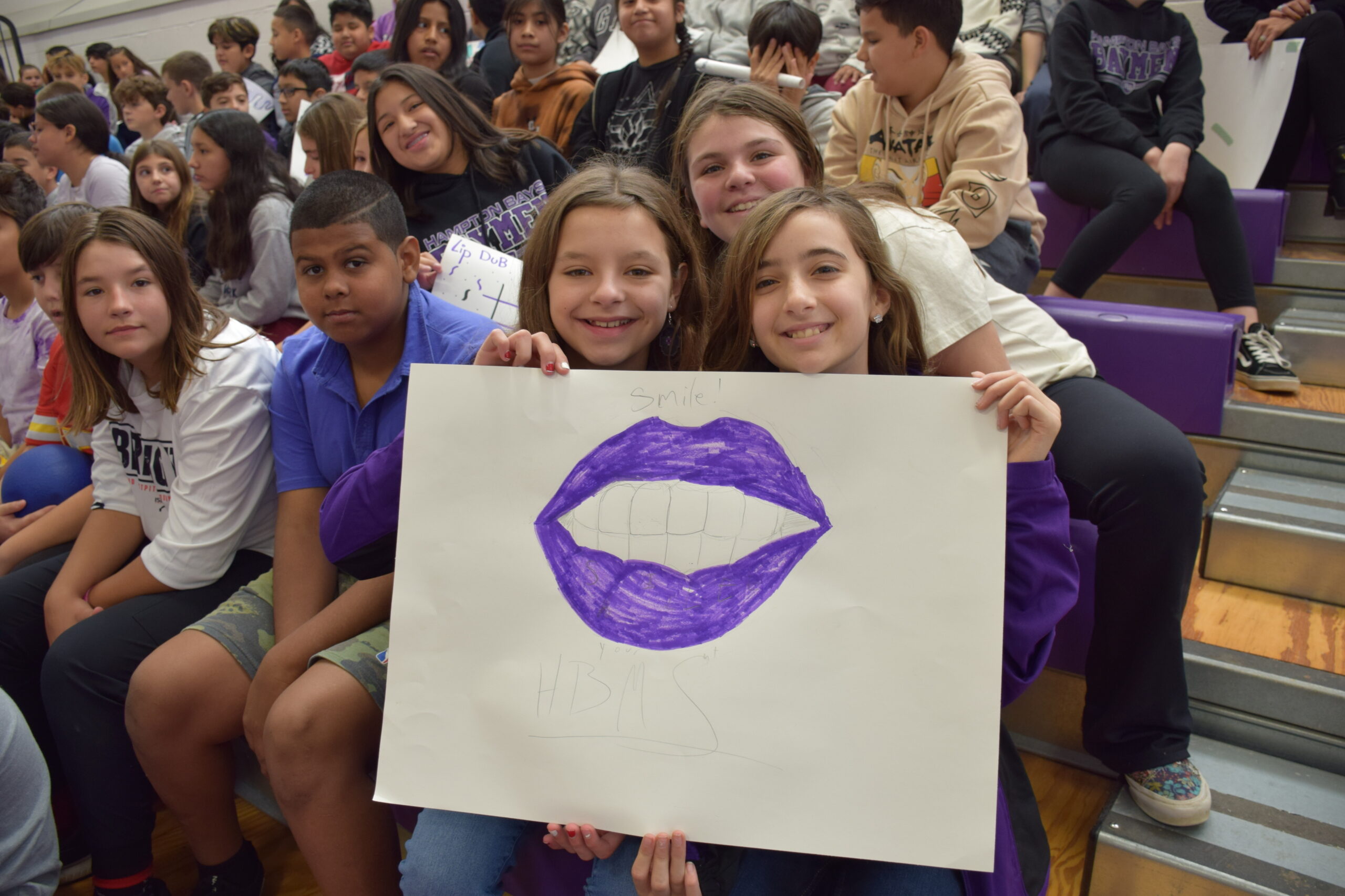 To foster unity at Hampton Bays Middle School, students and staff worked together to create a lip dub music video on November 22. Wearing purple, students lined their school’s hallways with signs and performed acts and dances while lip syncing to music as a camera passed them. This is the first time the school has come together for its traditional lip dub since the COVID-19 pandemic. The video is available for viewing on youtube.com. COURTESY HAMMPTON BAYS SCHOOL DISTRICT