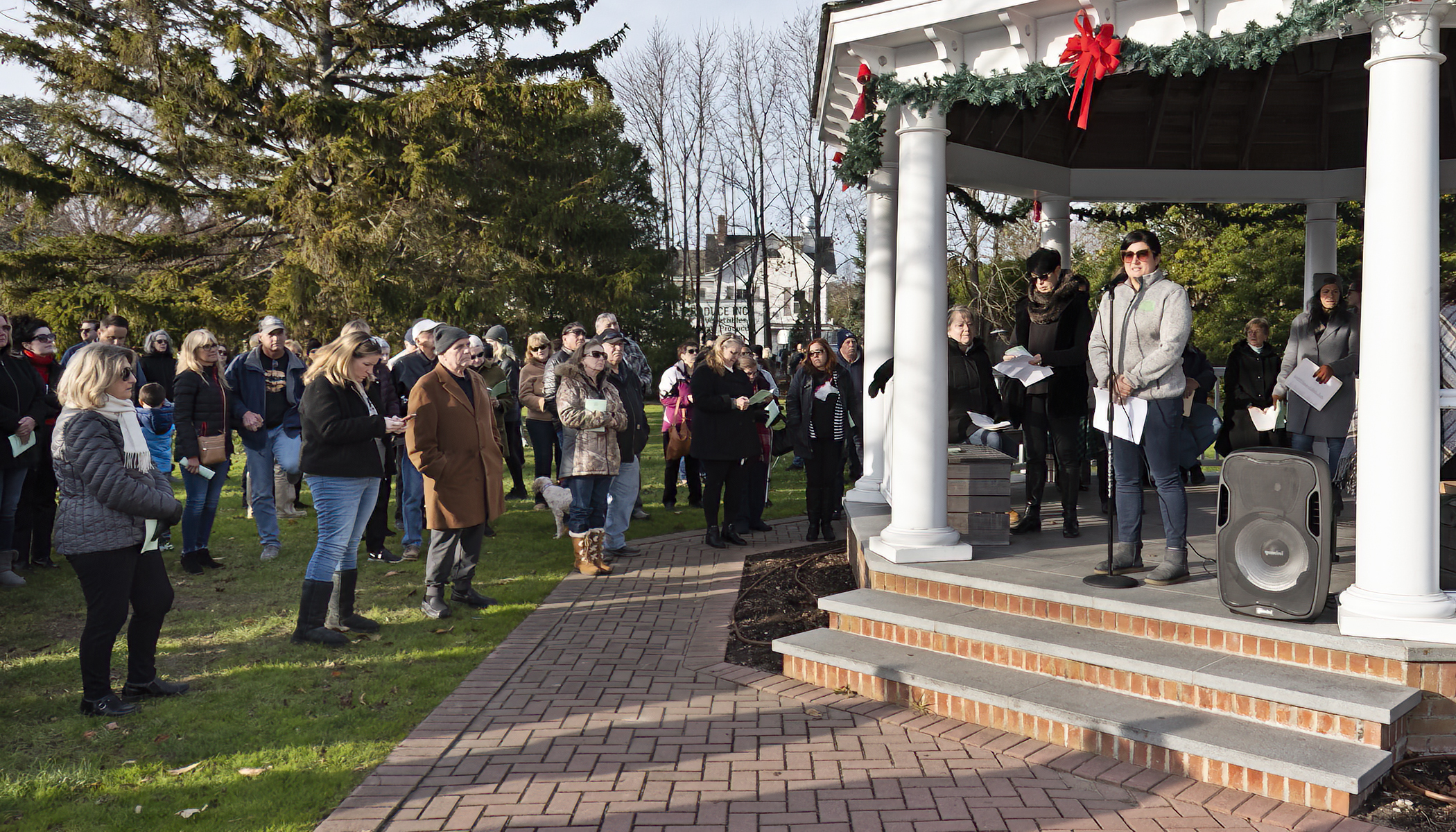 Mary Crosby, president and CEO of the East End Hospice, welcomed participants to the Hospice’s Tree of Lights Memorial Service on the Westhampton Beach Village Green on Sunday afternoon. Attended by approximately 200 people, the event memorialized friends and loved ones who have died. Similar events were held on the same day in Cutchogue and East Hampton. COURTESY EAST END HOSPICE