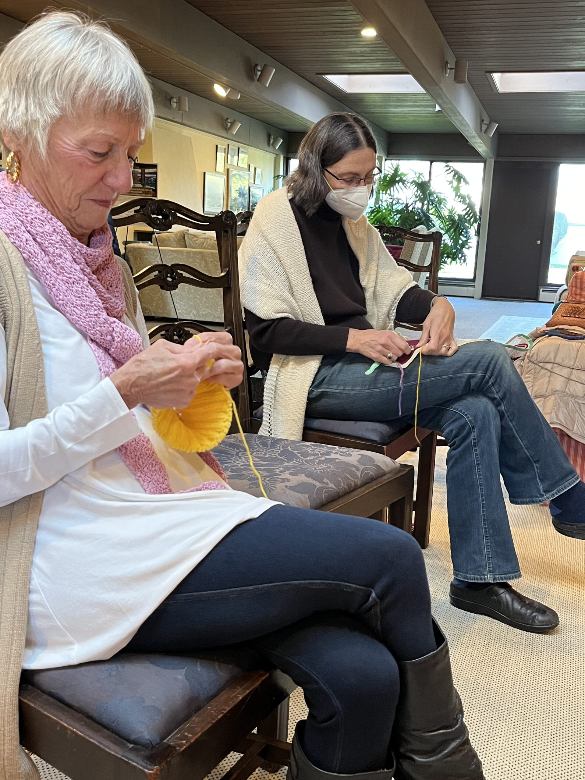 Barbara Albrecht knitting a yellow hat to be donated. Next to her, Ellen Greaves works on a needlepoint stitch for a seat cover to be donated to St. John’s Episcopal Church. ELIZABETH VESPE