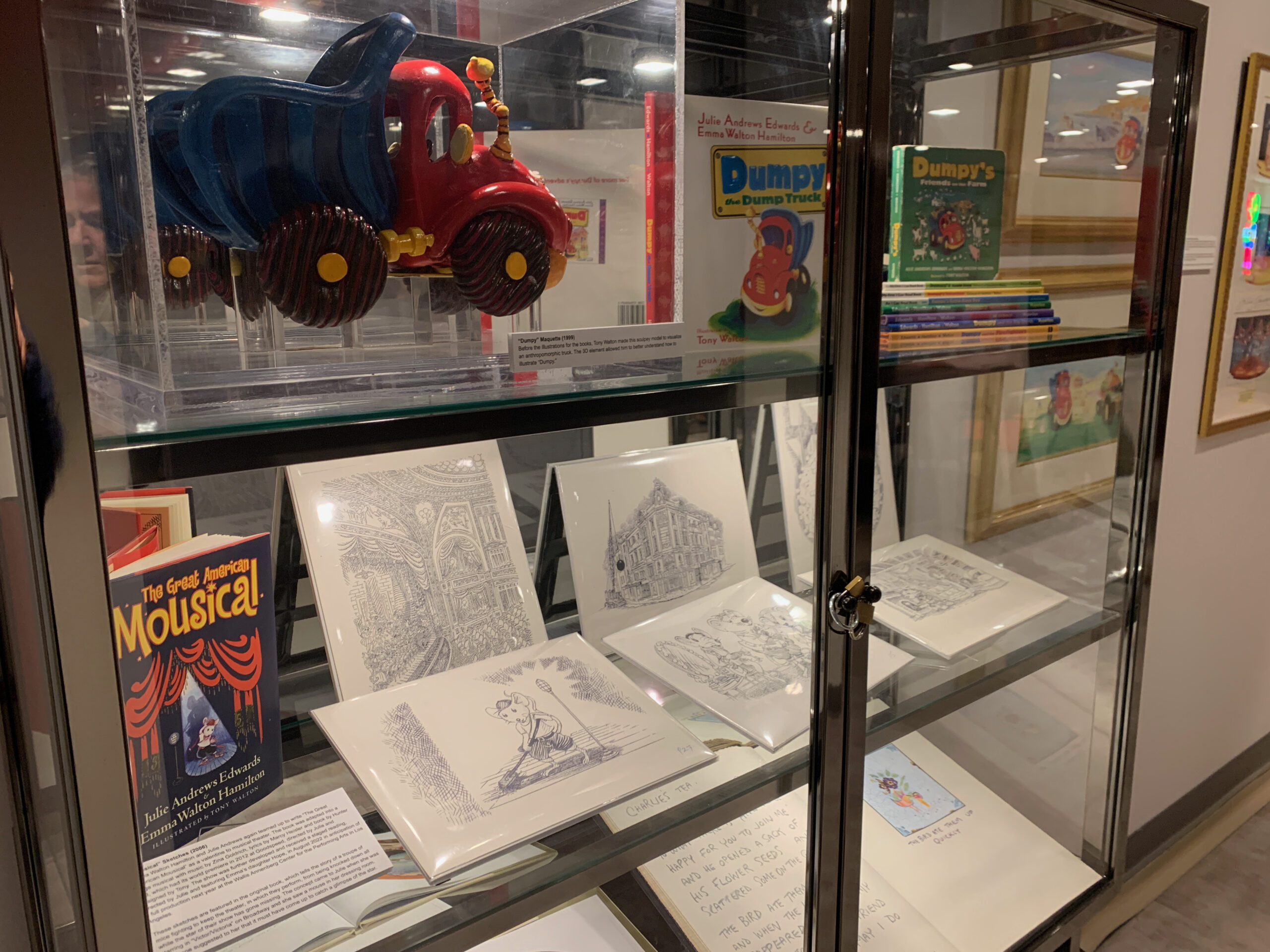 A display case highlighting children's books written as a collaboration between Emma Walton Hamilton and her parents Julie Andrews and Tony Walton. The objects are on view as part of 