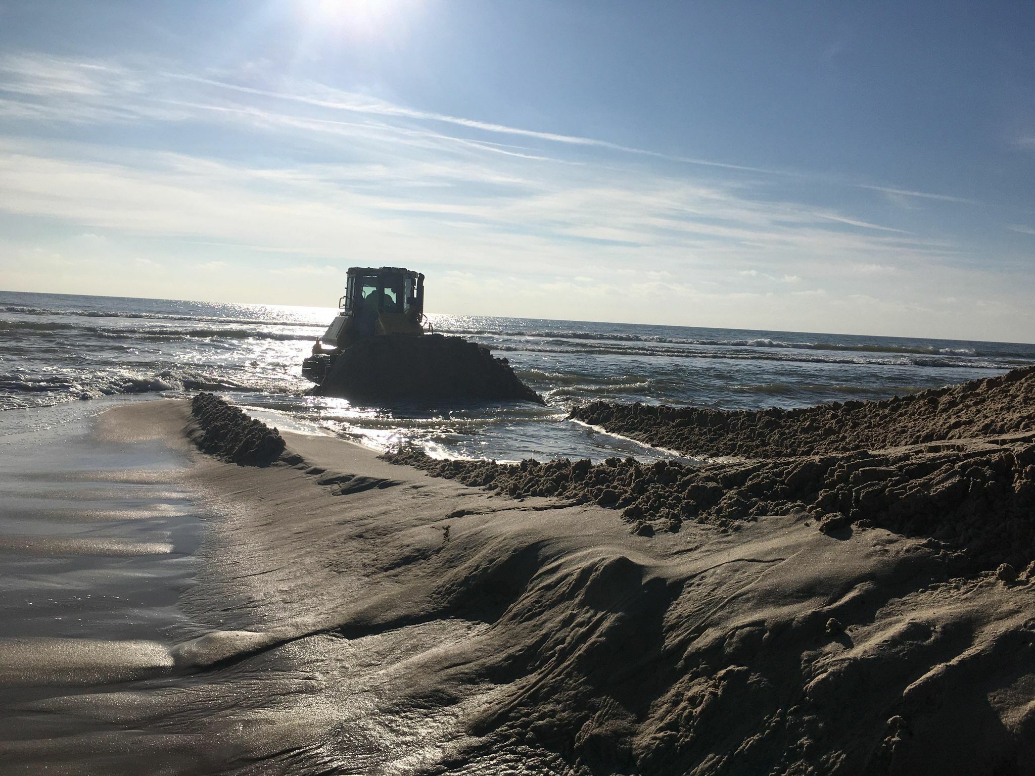 Out in the surf, the bulldozer crafts the sand mountain at the Mecox cut.    KITTY MERRILL