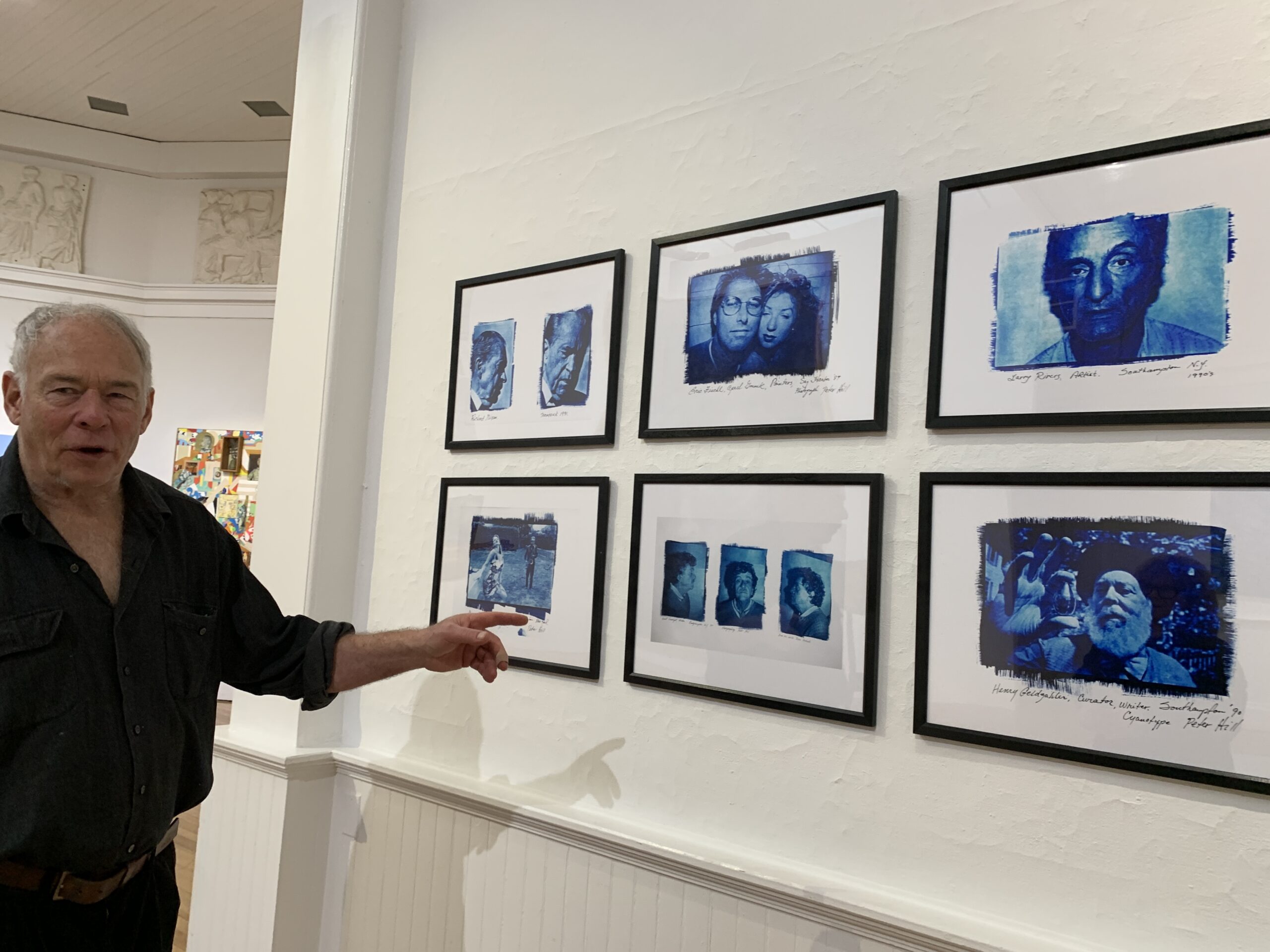 Artist and curator Paton Miller with Peter Hill's series of photographic prints of well-known East End artists on view in 