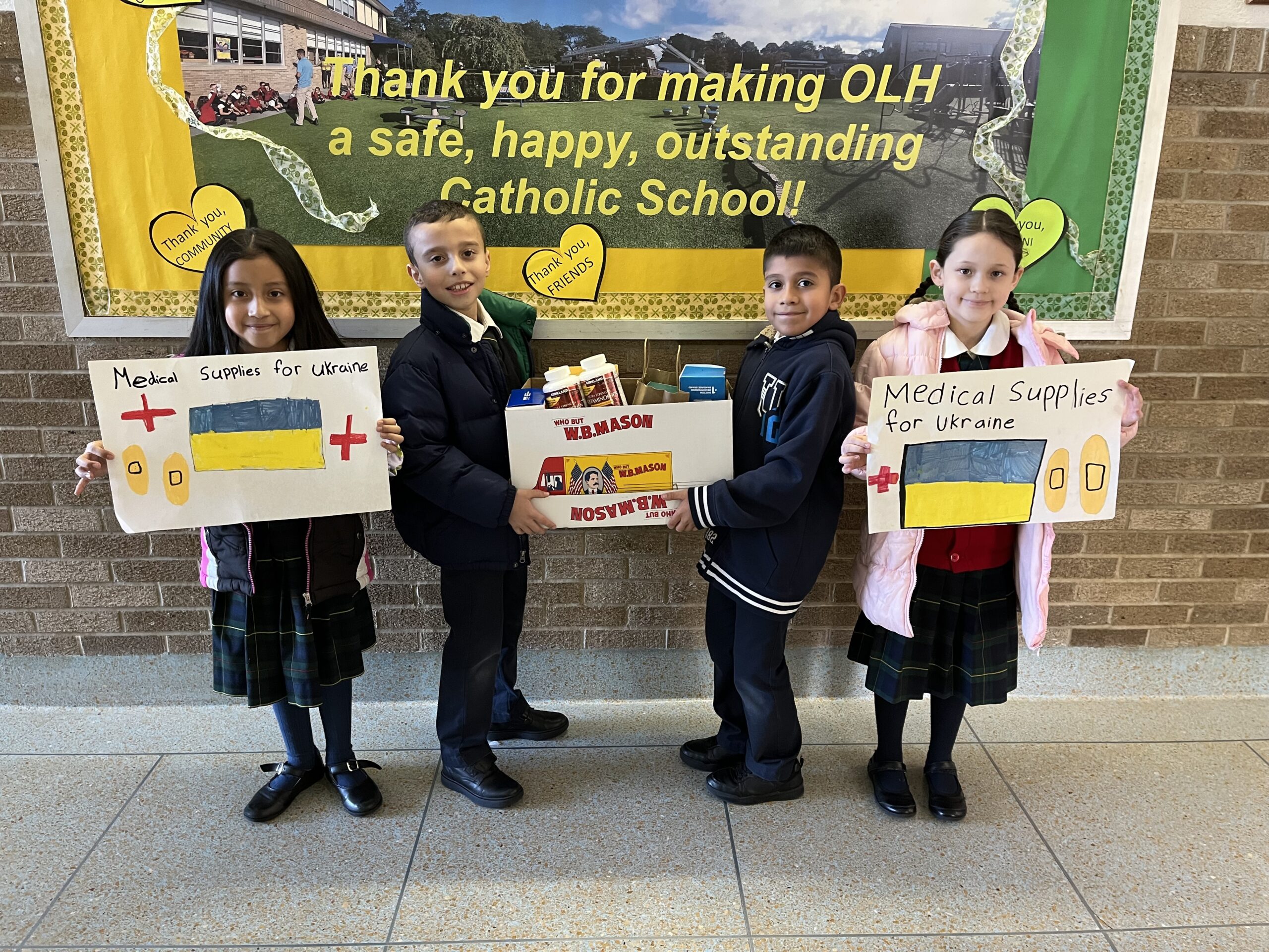 Our Lady of the Hamptons School third graders  Emely Lucero,  Jacob Cruz, Johan Garcia and Valentina Loja display their pleas for medical supplies for Ukraine.  COURTESY OUR LADY OF THE HAMPTONS SCHOOL