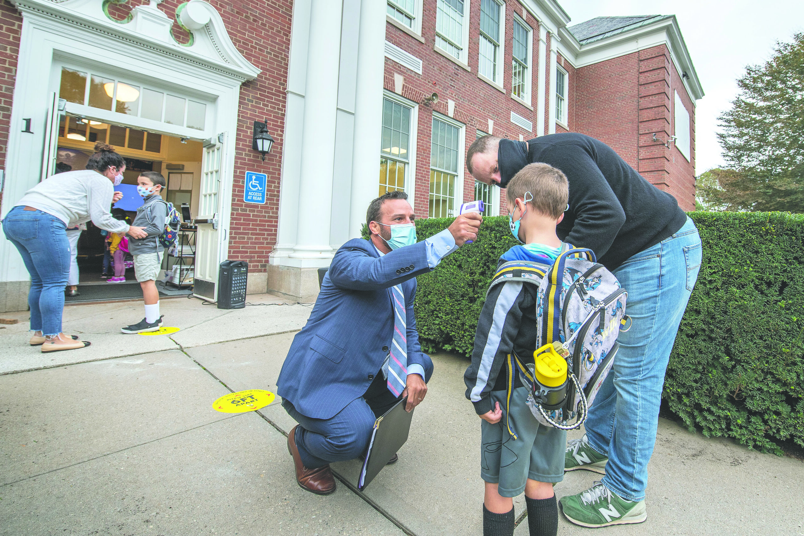 Bridgehampton School  Assistant Principal Michael Cox check's a little one's temperature before he goes inside the building on the first day of school at the Bridgehampton School on September 14, 2020.  MICHAEL HELLER