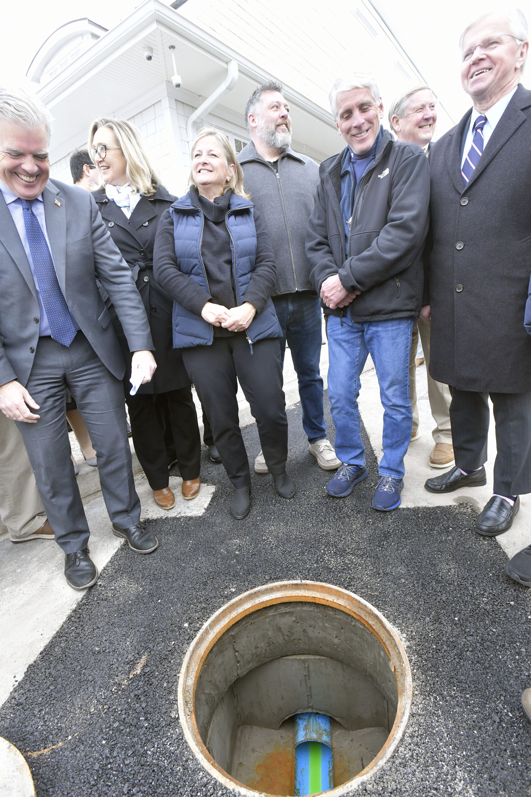 Officials watch as blue dyed water flows through the sewer pipe behind the Westhampton Free Library on Friday during a ceremonial 