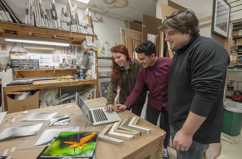 Hampton Photo Arts proprietor Ben McHugh and show organizer Eric Segura help photographer Lizzy Goldstein choose photos for printing to be included in the store's upcoming 