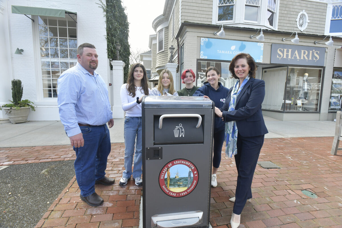 Southampton Village interim Superintendent of Public Works Steve Phillips, students Bea Fino Morofogen, Katie Terry and Riley Moredock, Natalie Sisco and Southampton Village Trustee Gina Arresta with one of the Bigbelly trash cans on Main Street.    DANA SHAW
