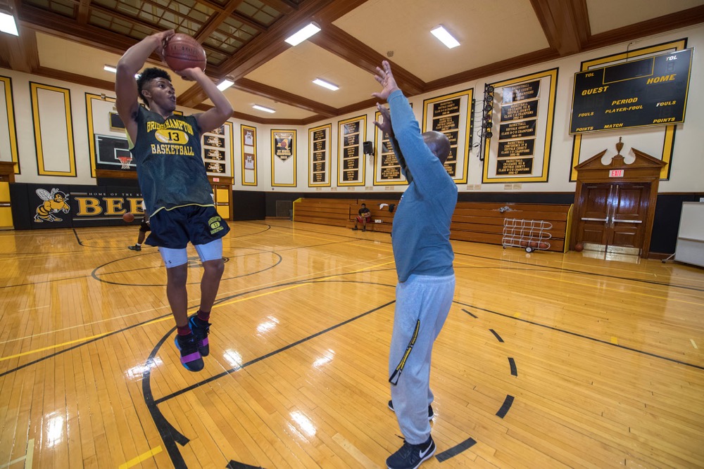 Bridgehampton Killer Bees coach Ron White works with his son Elijah during a team practice in the school's gymnasium on Monday evening