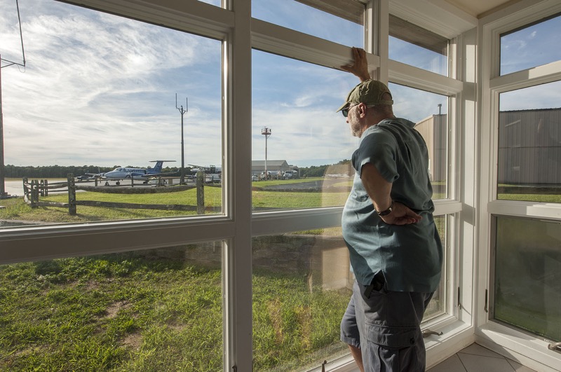 David Gruber of the newly-re-formed East Hampton Airport Noise Citizen's Advisory Committee watches private jets discharge their passengers from inside the terminal during a fact-finding trip to the airport on Friday