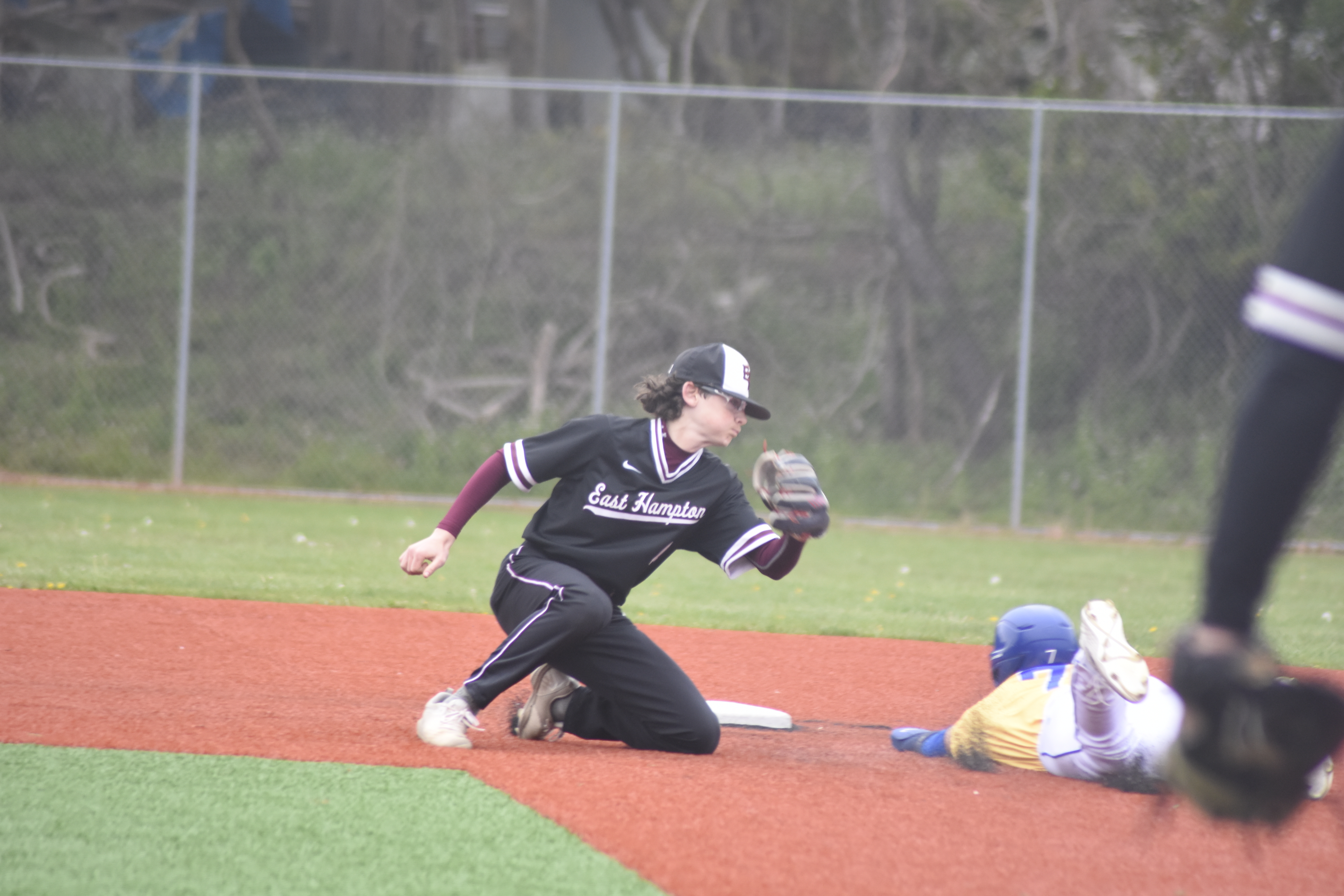 East Hampton shortstop Hudson Meyer tries to tag out a Comsewogue runner trying to steal second base on a close play.   DREW BUDD