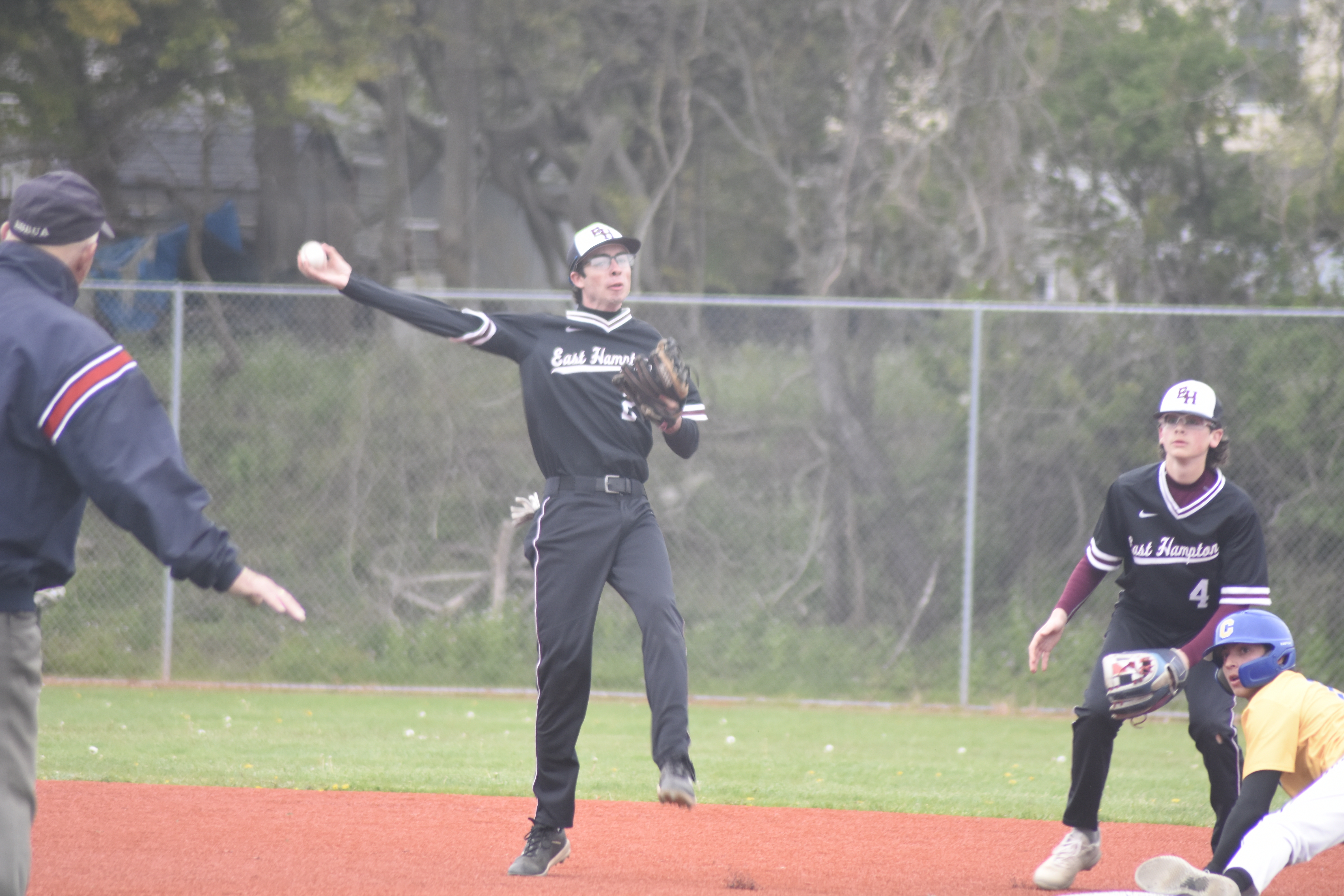 East Hampton second baseman Hunter Eberhart throws across his body to get an out a first after fielding a bouncing ball up the middle.   DREW BUDD