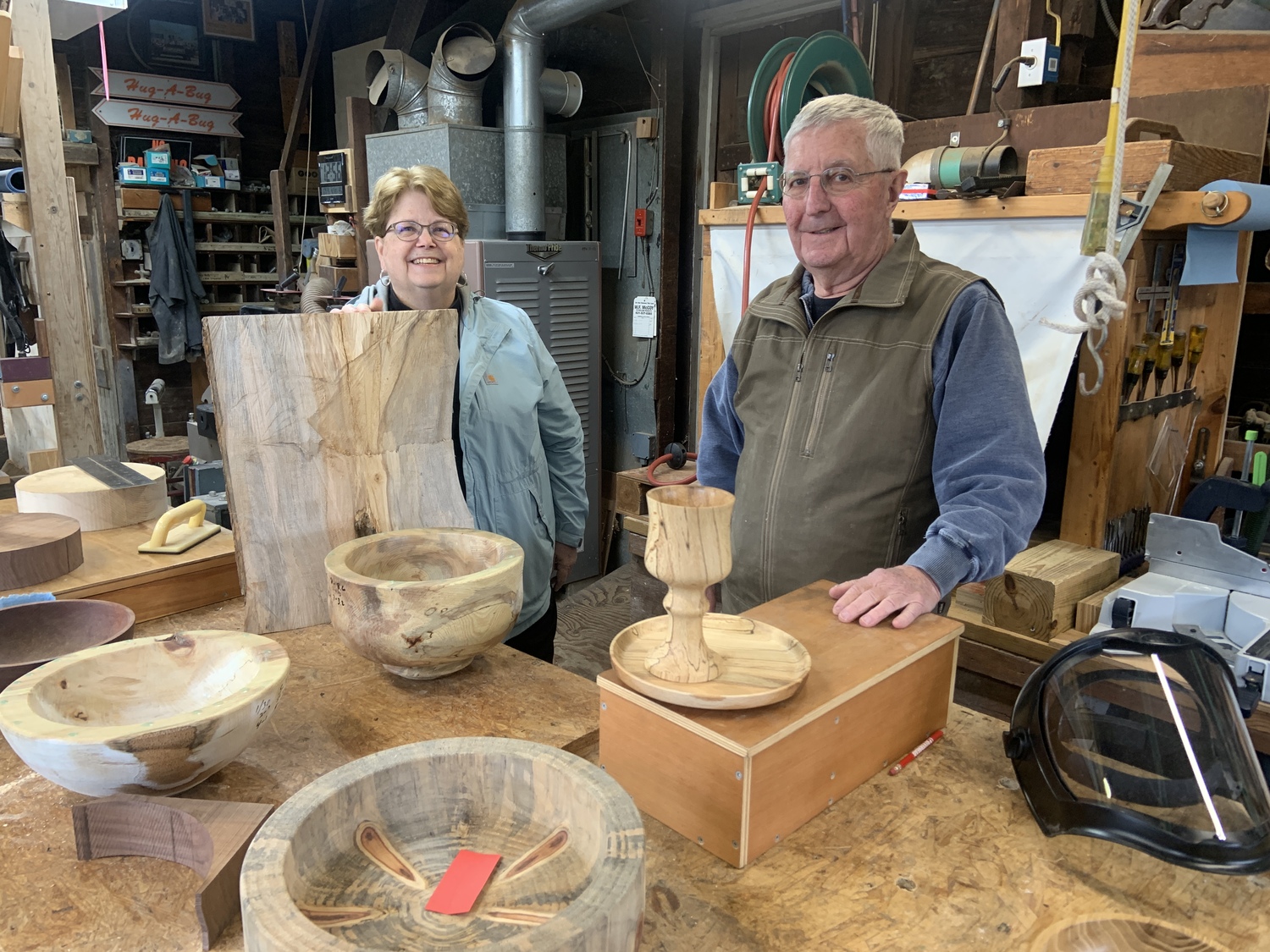 The Reverend Joanne Utley,  with a piece of unfinished beechwood, in John Halsey's Mecox wood shop. The Communion set he made for her sits in front of him. STEPHEN J. KOTZ