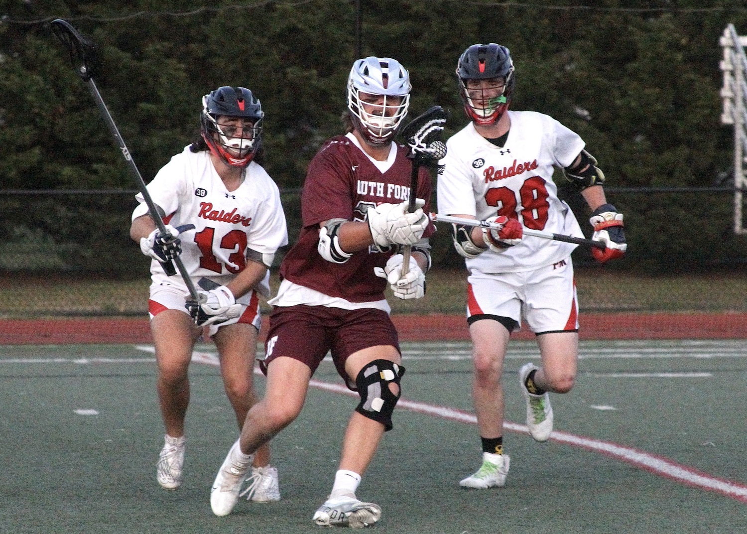 Junior midfielder Charlie Corwin grabs the ball with two Patchogue-Medford defenders on his back. DESIRÉE KEEGAN