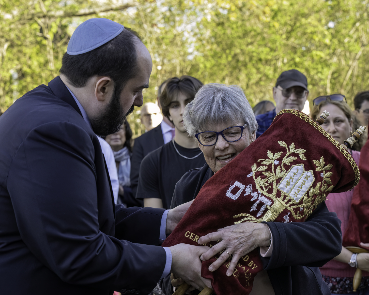 Rabbi Daniel Geffen assists Gail Gambino who carried one of four Torahs that were returned to Temple Adas Israel. MARIANNE BARNETT