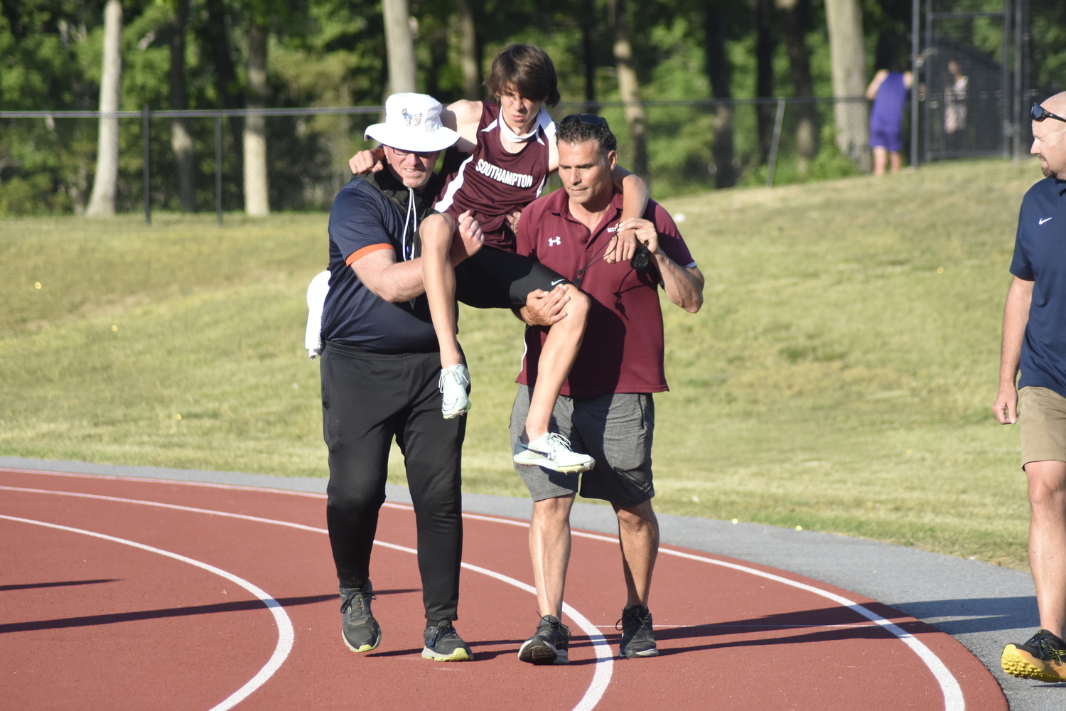A trainer and Southampton coach Eddie Arnold help Tanner Marro off the track after an injury.   DREW BUDD