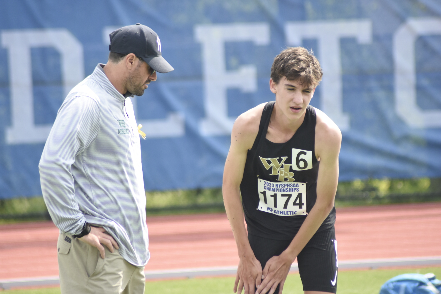 Trevor Hayes shows head coach Joe Mensch where he was cramping up during the race.   DREW BUDD