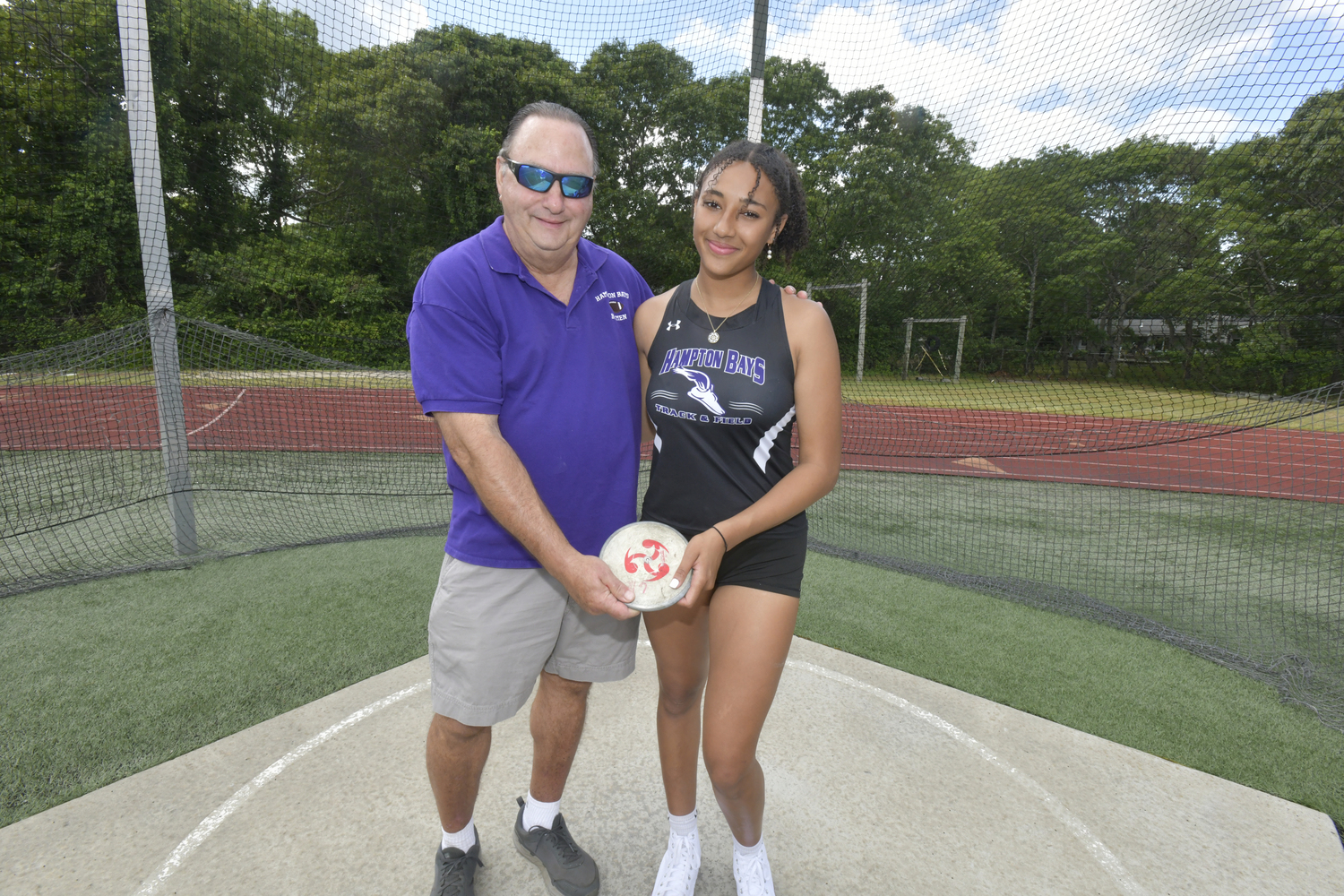 Asha Pensa-Johnson with her grandfather Charlie Pensa in the discus circle at Hampton Bays High School.    DANA SHAW
