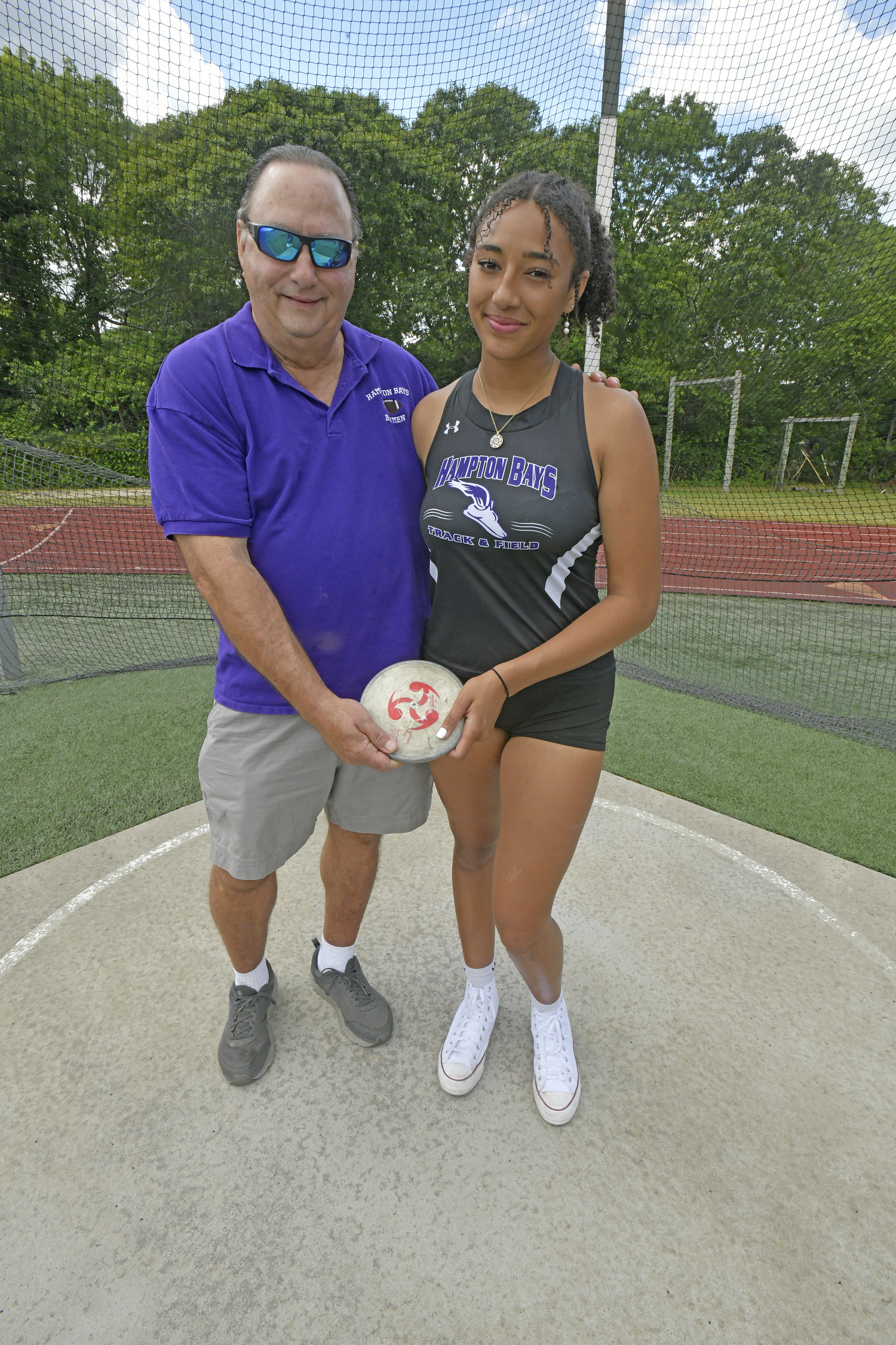 Asha Pensa-Johnson with her grandfather, Charlie Pensa in the discus circle at Hampton Bays High School.    DANA SHAW