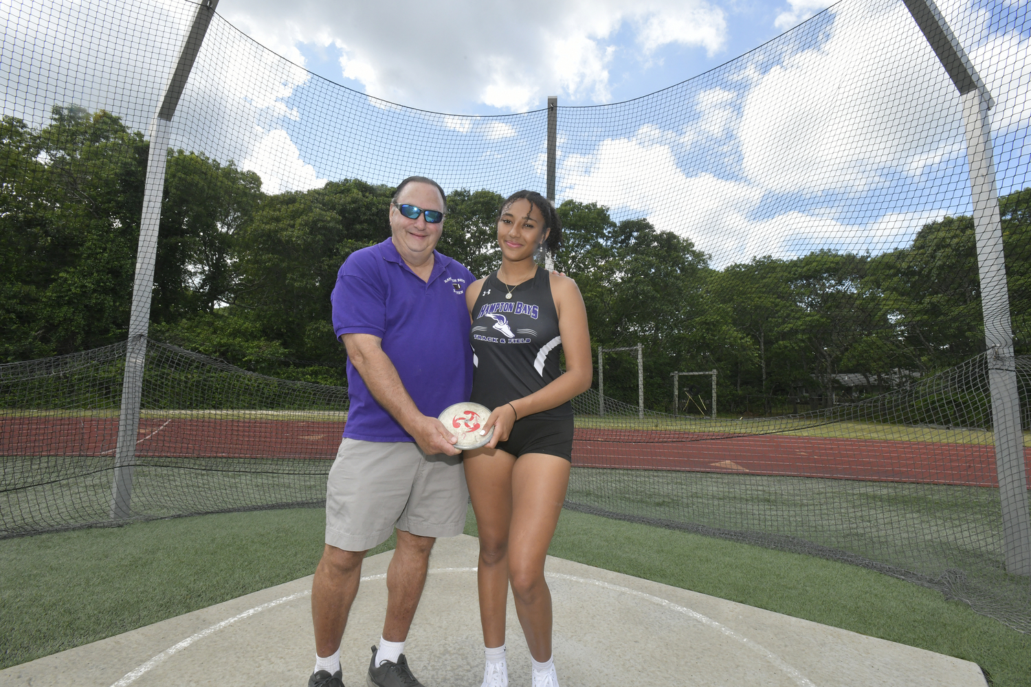 Asha Pensa-Johnson with her grandfather Charlie Pensa in the discus circle at Hampton Bays High School. DANA SHAW