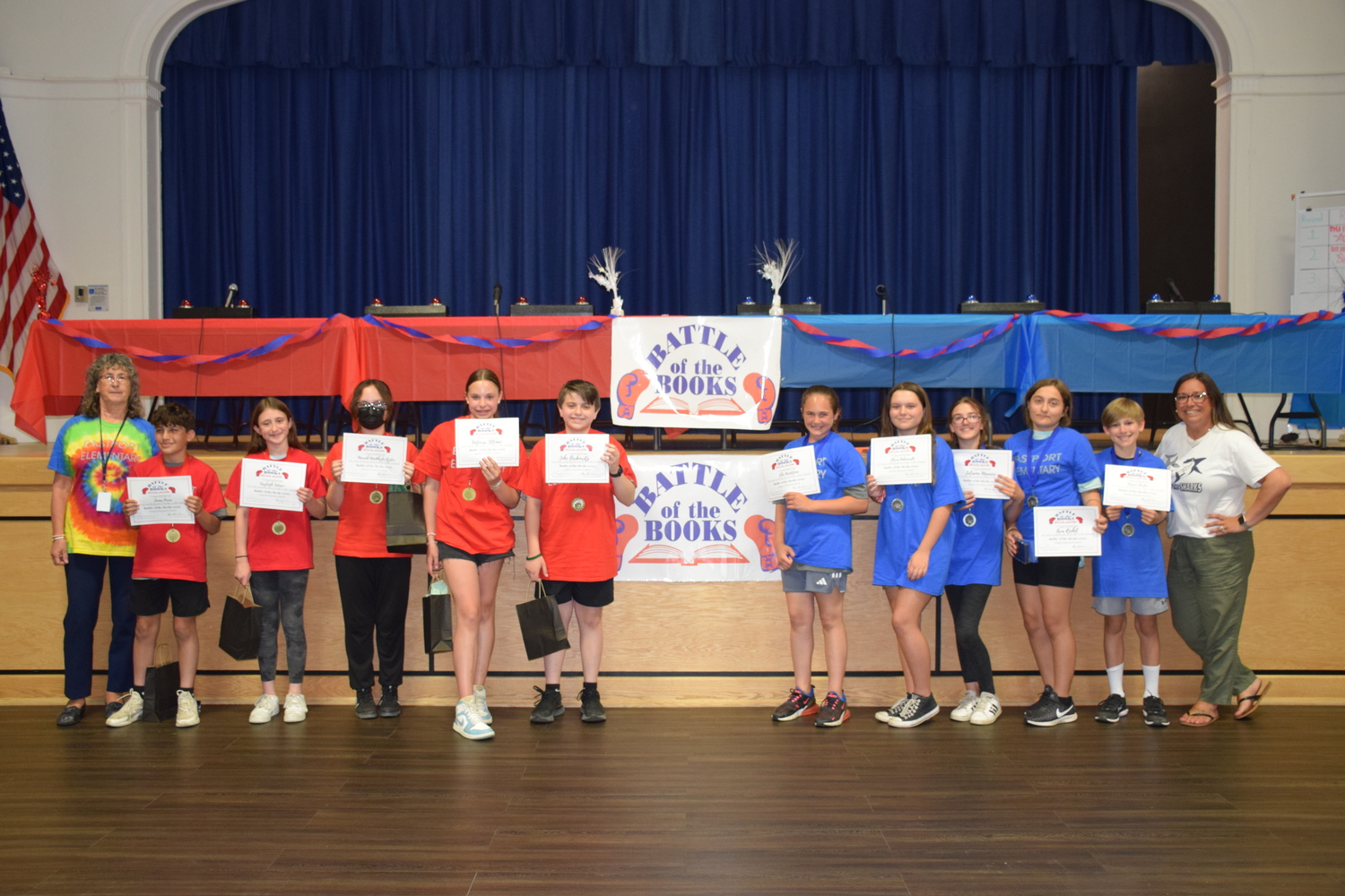 Eastport Elementary School library teacher aide Barbara Fernandez and, right, library media specialist Alyssa Sorenson with Team Red and Team Blue after the 10th annual Battle of the Books. COURTESY EASTPORT-SOUTH MANOR SCHOOL DISTRICT