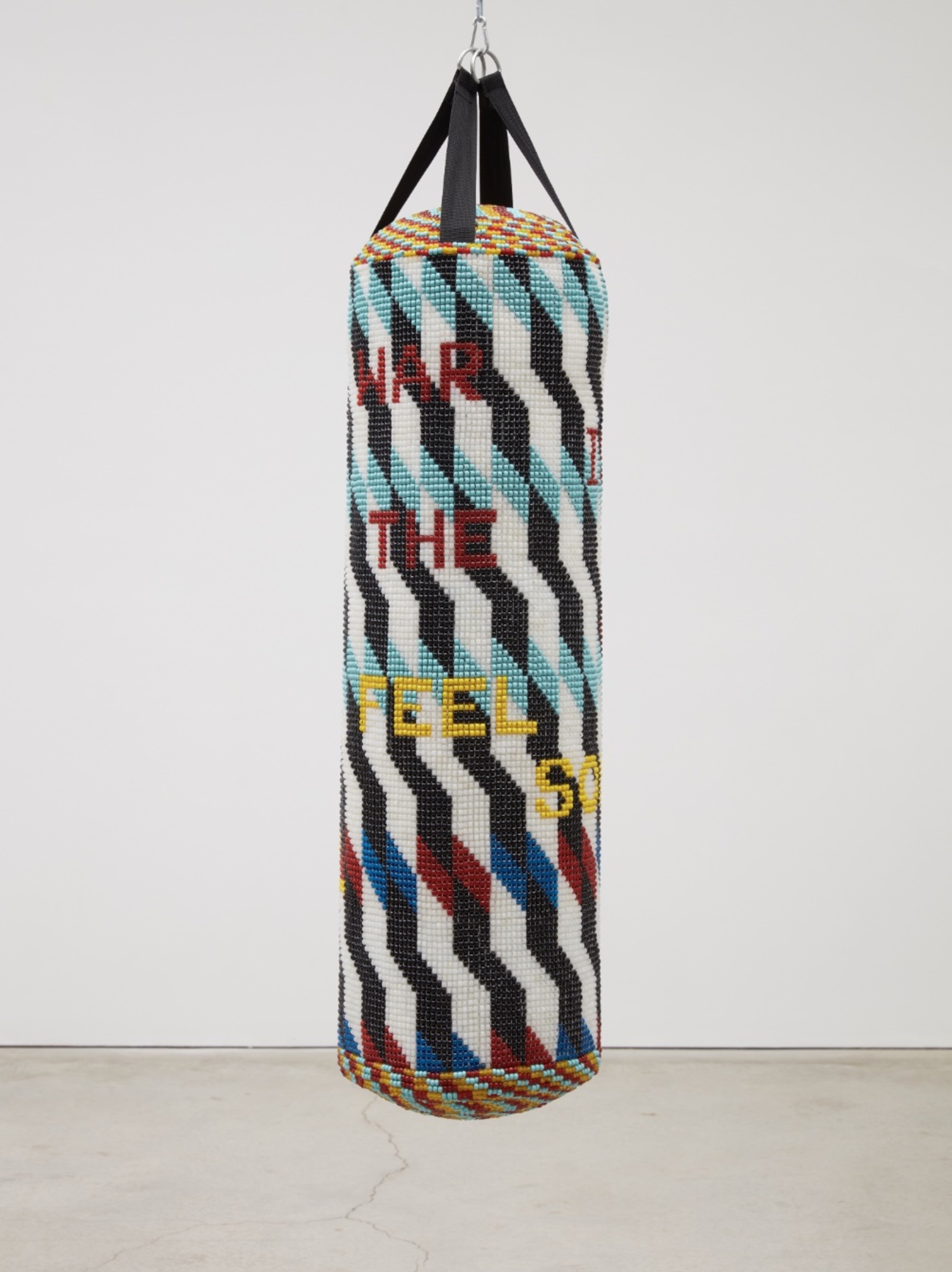 Jeffrey Gibson, “WAR IS NOT THE ANSWER FEEL SOEMTHING REAL,” 2020. Repurposed punching bag, acrylic felt, glass beads, artificial sinew, 57” x 15” x 15.” © JEFFREY GIBSON, COURTESY THE ARTIST AND COLLECTION OF BECKY GOCHMAN