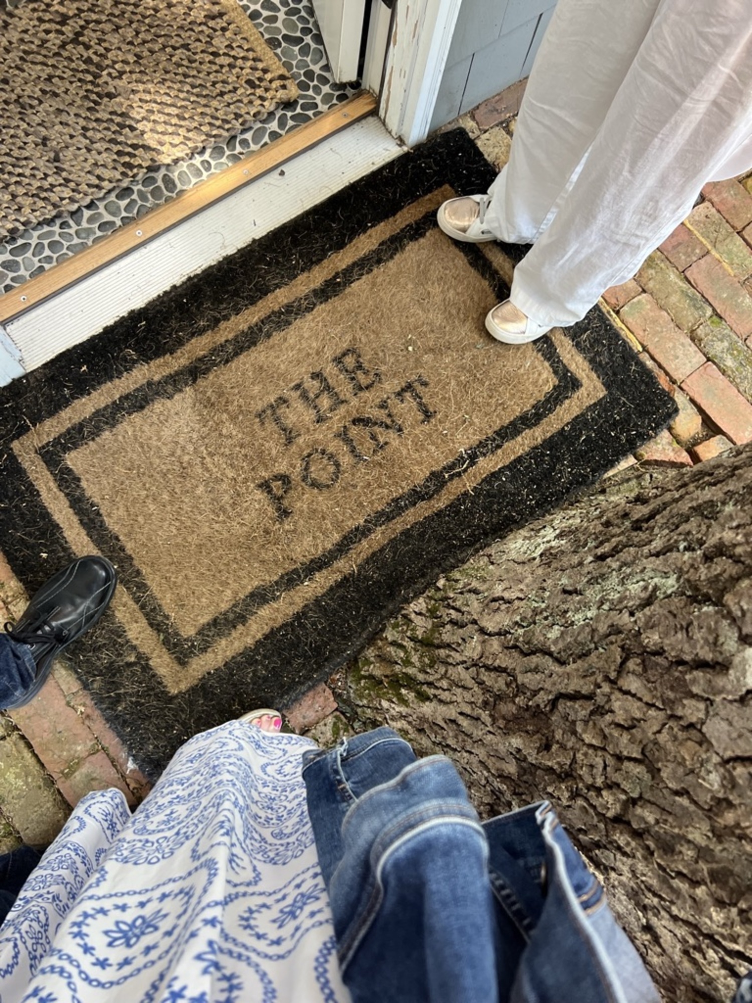 In between the front door and the tree lies a door mat labeled 