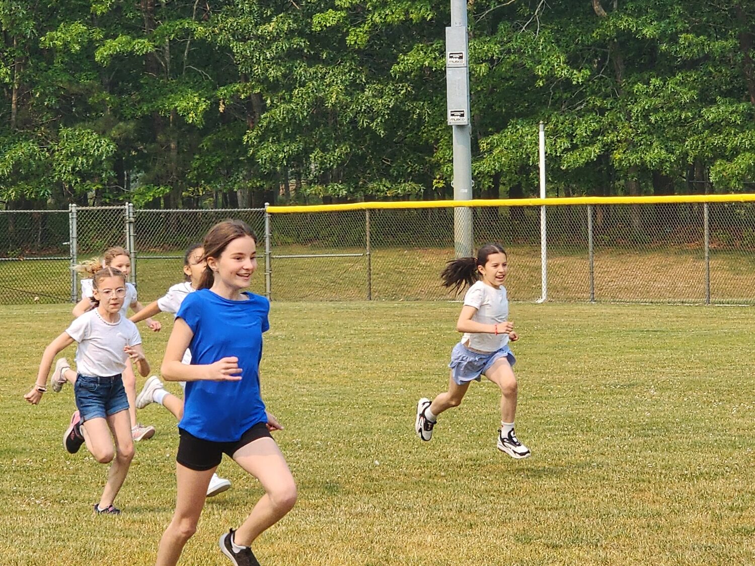 Our Lady of the Hamptons School students and staff gathered for a day of fun and outdoor activities at Field Day ’23 at Red Creek Park in
Hampton Bays recently, at which blue team member fifth-grader Mira Uniiat edges her white team rival at field day The day was planned by athletic directors Ben Turnbull and Elyse Curro. COURTESY OUR LADY OF THE HAMPTONS SCHOOL