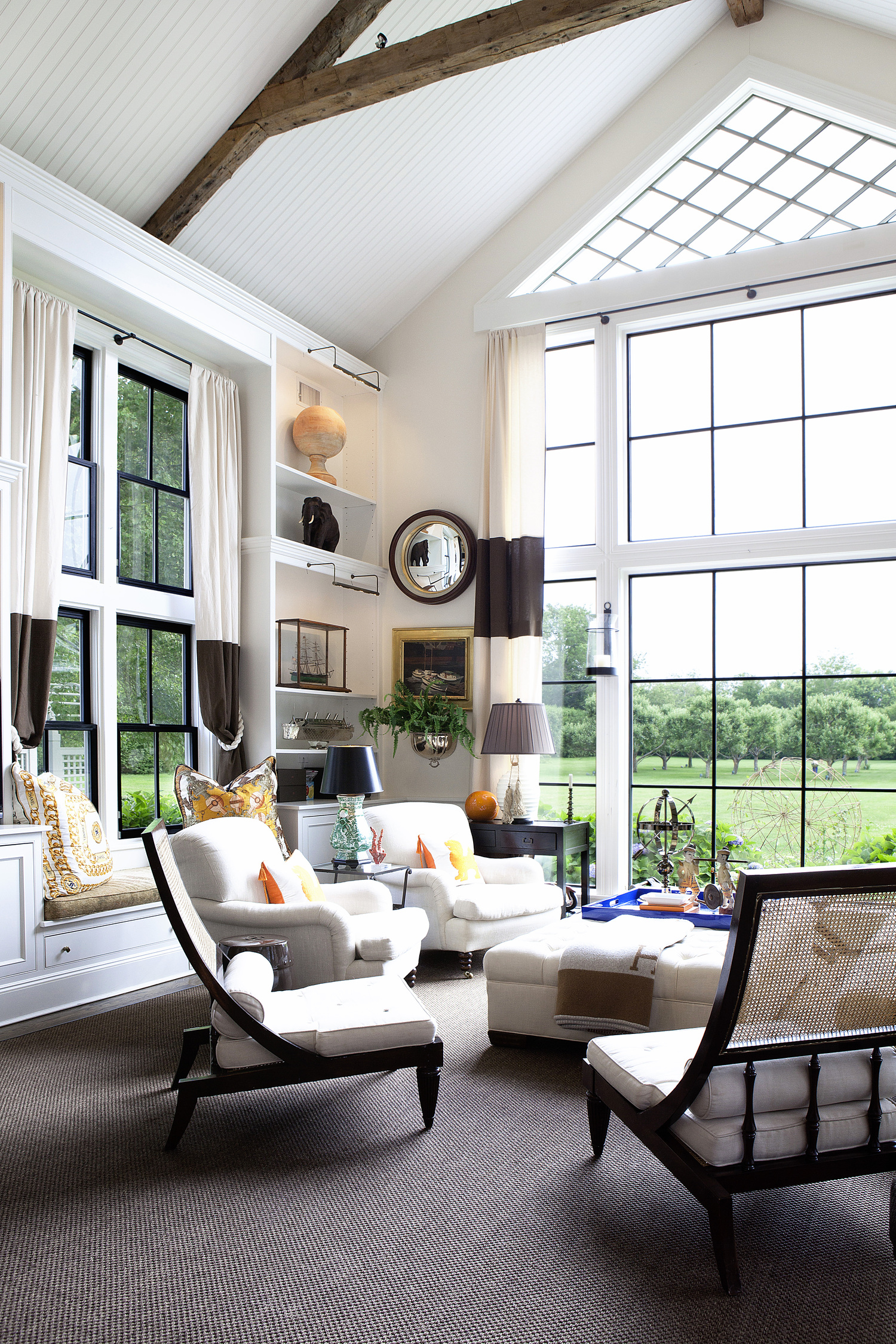 The living room is a soaring space, capped by a triangular, diamond paned gable window. DLUXCREATIVE