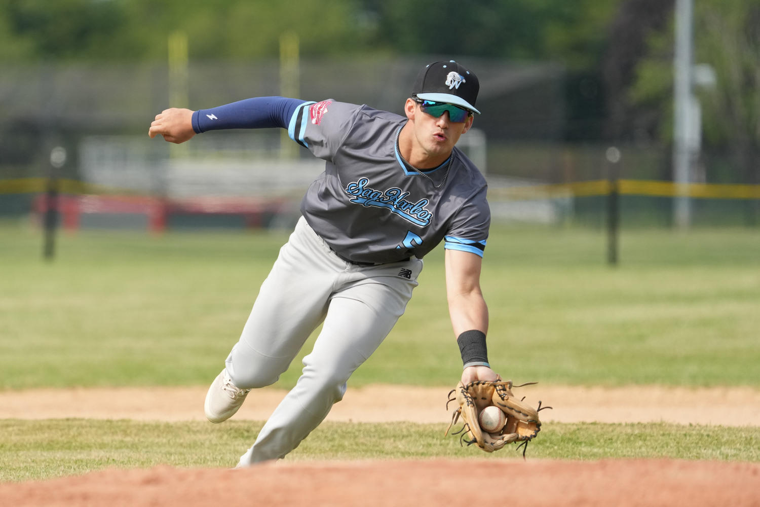 Sag Harbor's Milo Suarez (Dartmouth) scoops up a ground ball.   RON ESPOSITO