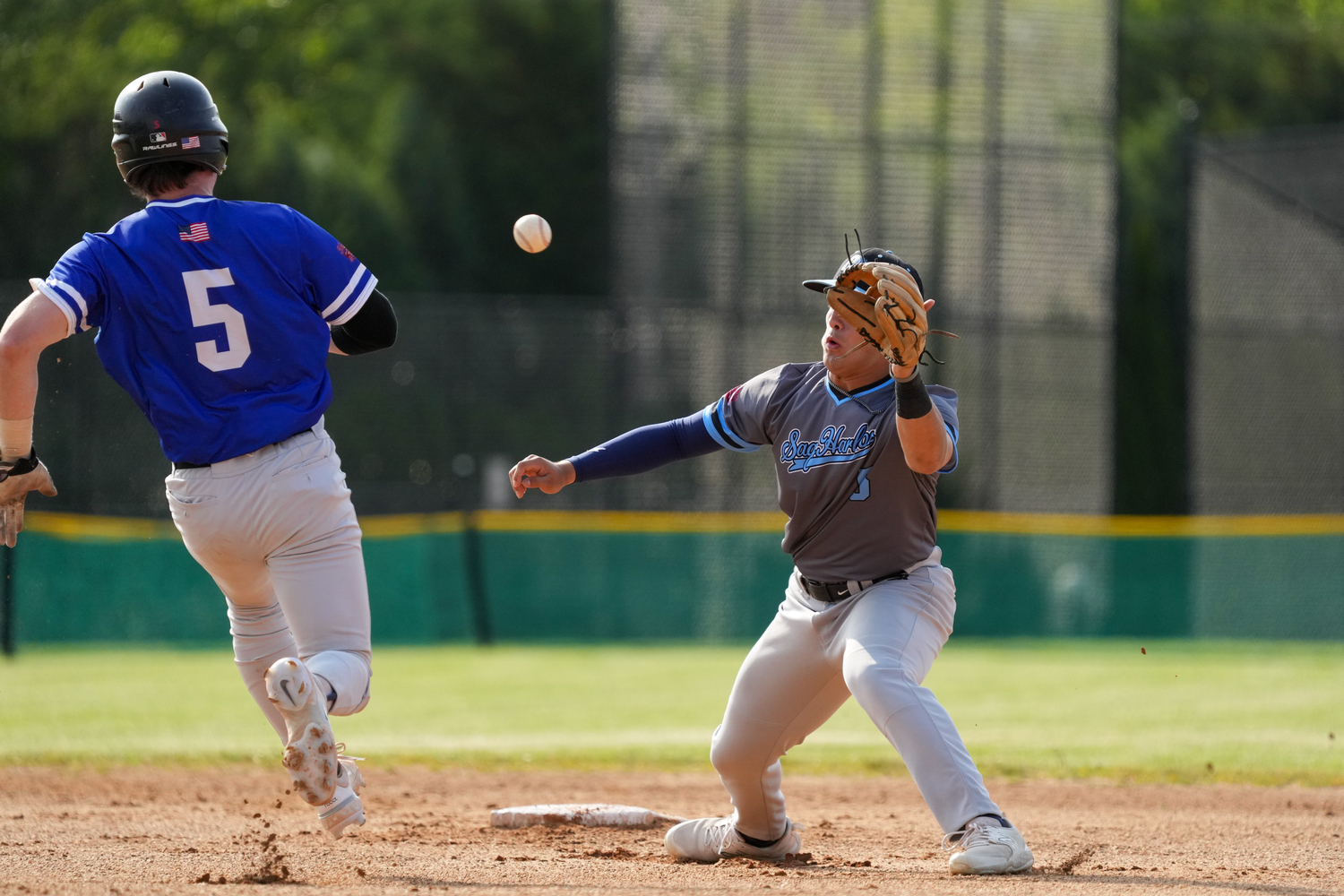 Sag Harbor's Wyatt Benson (Orange Coast) takes a throw with Southampton's Ty Gilligan (Dominican) bearing down on him.  RON ESPOSITO