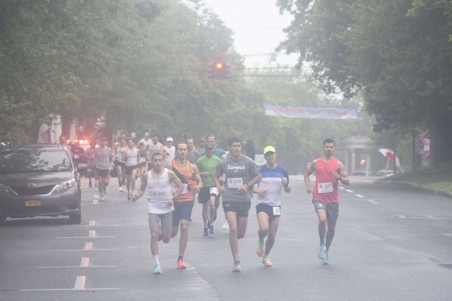 Runners make the first turn off Jobs Lane onto South Main Street at the start of the 32nd annual Firecracker 8K in Southampton on Sunday morning.   DREW BUDD