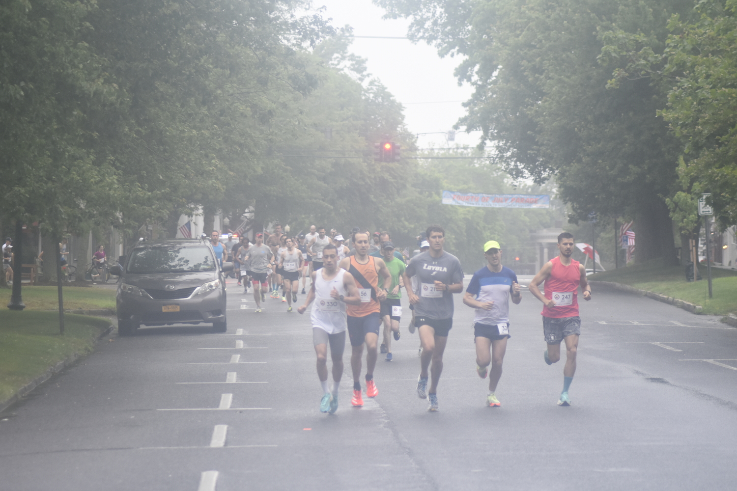 Runners make the first turn off Jobs Lane onto South Main Street at the start of the 32nd annual Firecracker 8K in Southampton on Sunday morning.   DREW BUDD