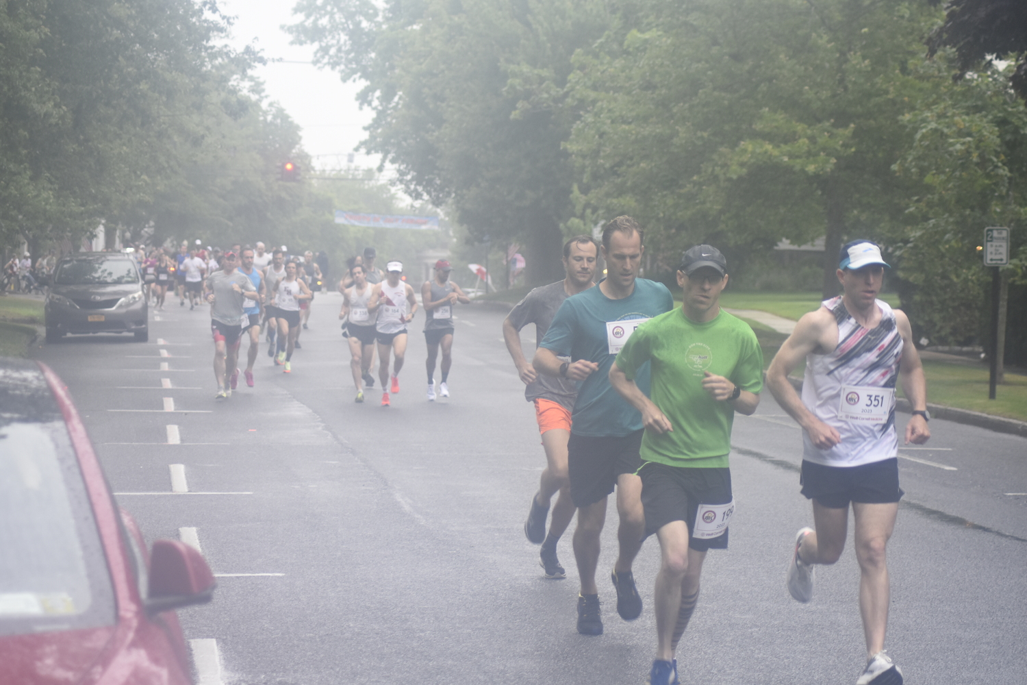 Runners make the first turn off Jobs Lane onto South Main Street at the start of the 32nd annual Firecracker 8K in Southampton on Sunday morning.   DREW BUDD