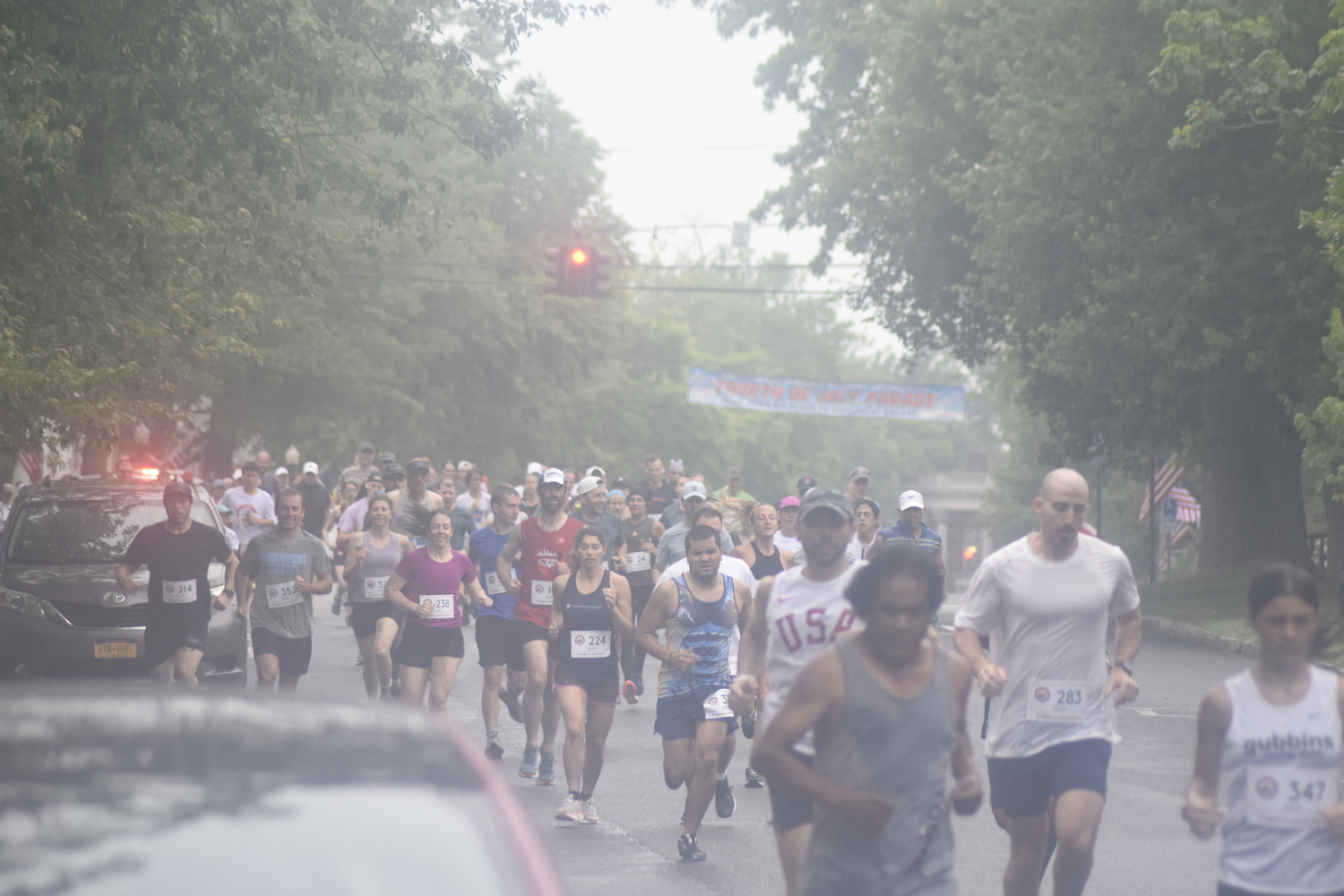 Runners make the first turn off Jobs Lane onto South Main Street at the start of the 32nd annual Firecracker 8K in Southampton on Sunday morning.   DREW BUDD