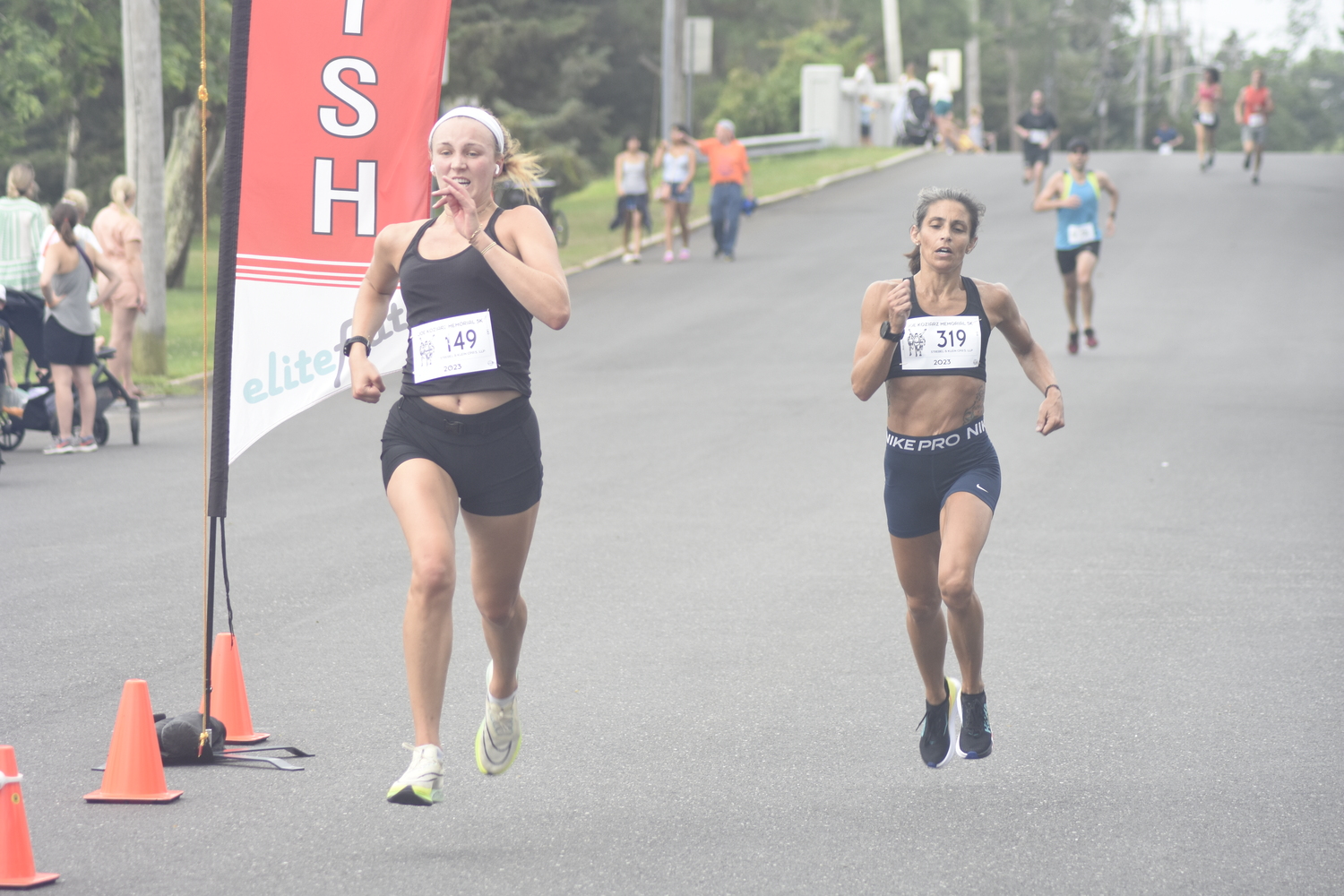 Katie Gleason, left, and Tara Farrell cross the finish line almost instantaneously to round out the top six women finishers.    DREW BUDD