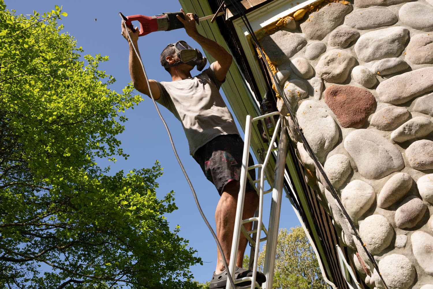 Mica Marder cuts into the side of a home wherethere is a bee infestation.