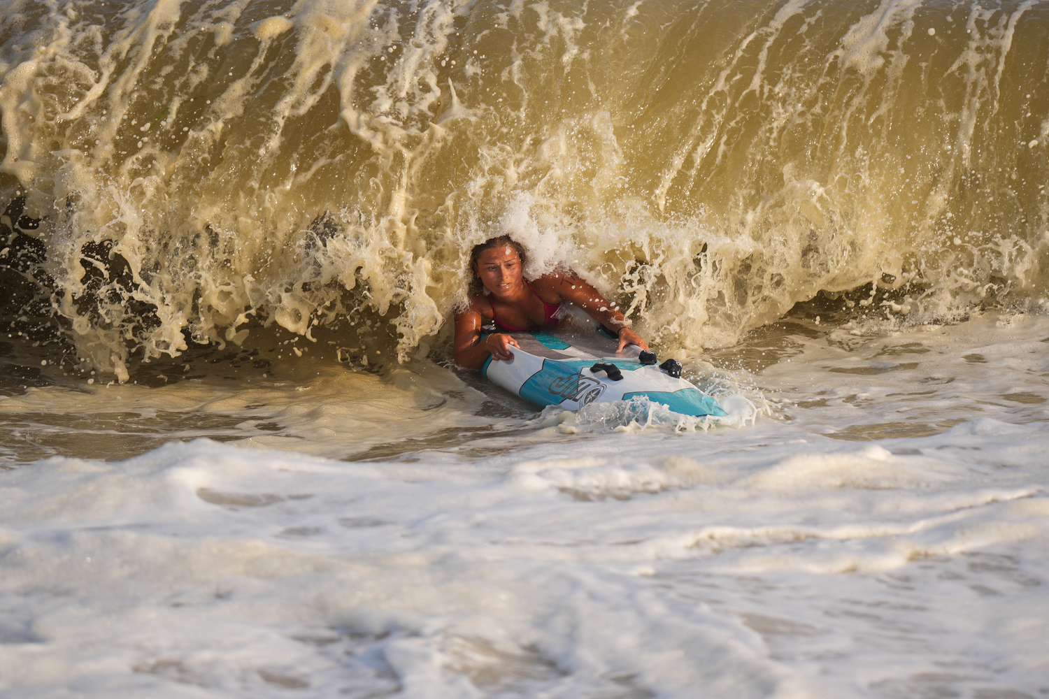 East Hampton Town Lifeguard Sophia Swanson gets devoured by the surf during the paddle board relay.  RON ESPOSITO