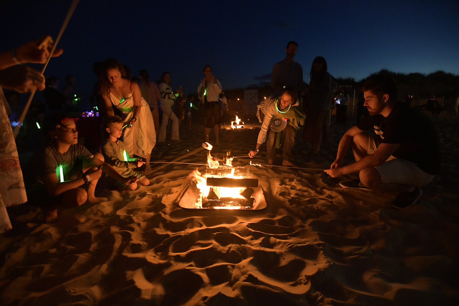 Participants of the Moonlit Plunge for Heart of the Hamptons toast marshmallows after their dip on Tuesday night at Coopers Beach.  DANA SHAW