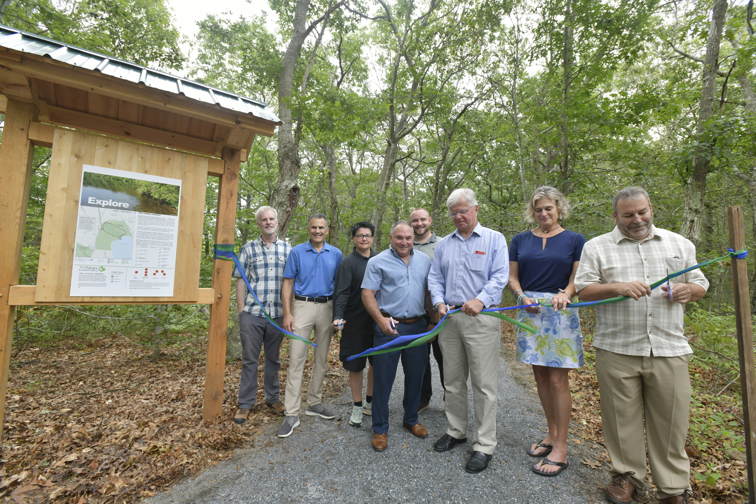 The Nature Conservancy celebrates the completion of a new universal access trail at Wolf Swamp Preserve in North Sea on August 24. The new half-mile loop is designed and built per federal accessibility guidelines that can accommodate strollers, wheelchairs, and visitors with other mobility needs or challenges. Big Woods and Wolf Swamp Preserve are open 7 days a week from sunrise to sunset and are free. Cutting the ribbon are left to right, Kevin Munroe, William Parash, Gina Damaro, Scott Horwitz, Darryl Baumer Jr., Fred W. Thiele Jr., Ann Welker and Joe Jannsen.  DANA SHAW