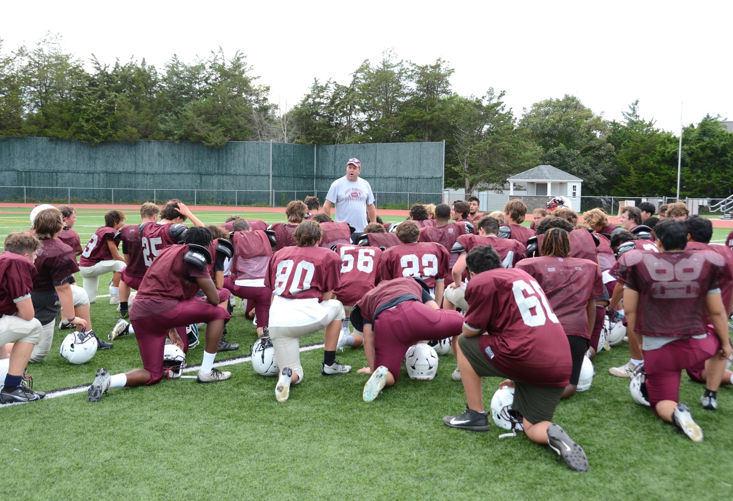 East Hampton football head coach Joe McKee talks to his players before practice on Monday.   KYRIL BROMLEY