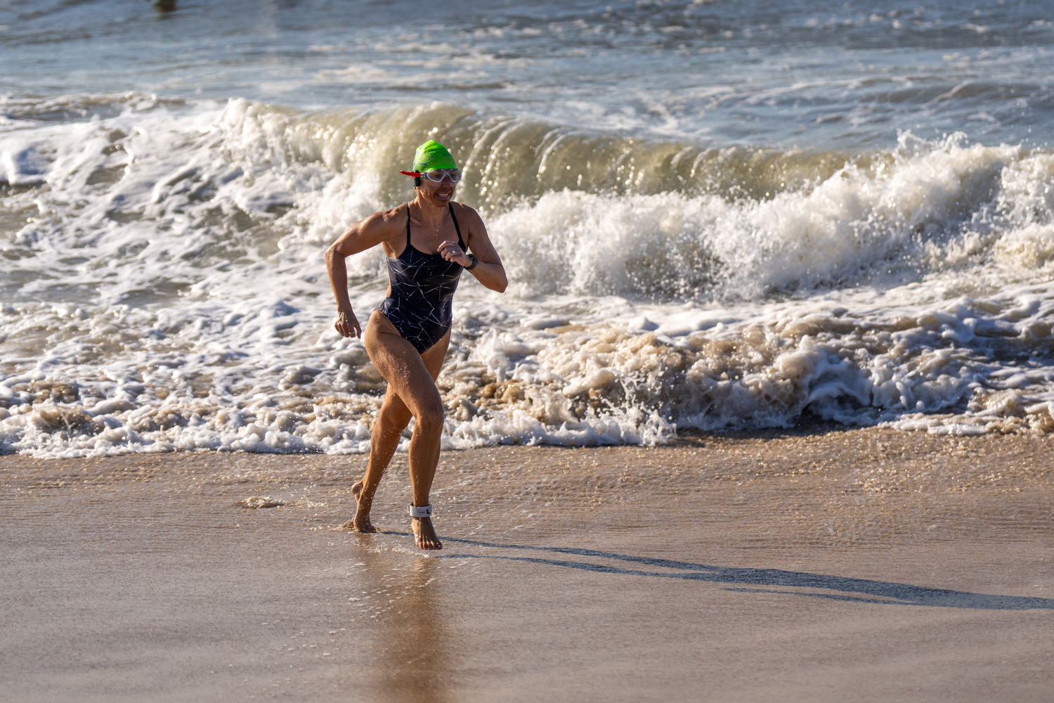 A swimmer gets out of the water and heads toward the finish line.   RON ESPOSITO