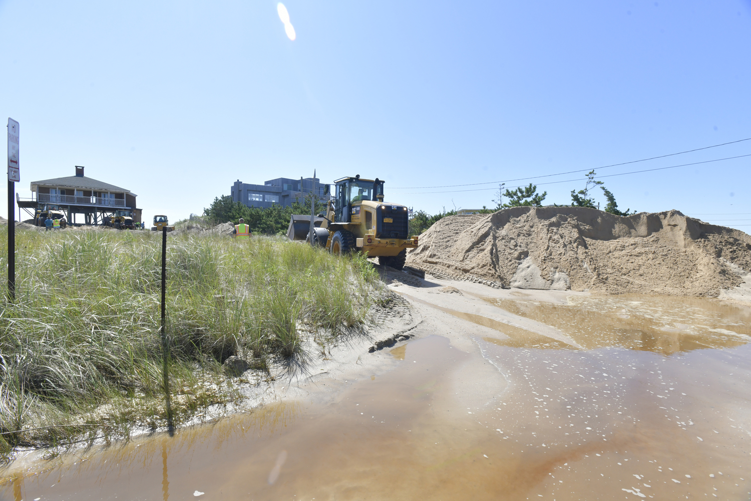 Crews work on removing sand from Dune Road, just east of Sandbar Beach in East Quogue on Thursday after a breach on Wednesday night.  DANA SHAW