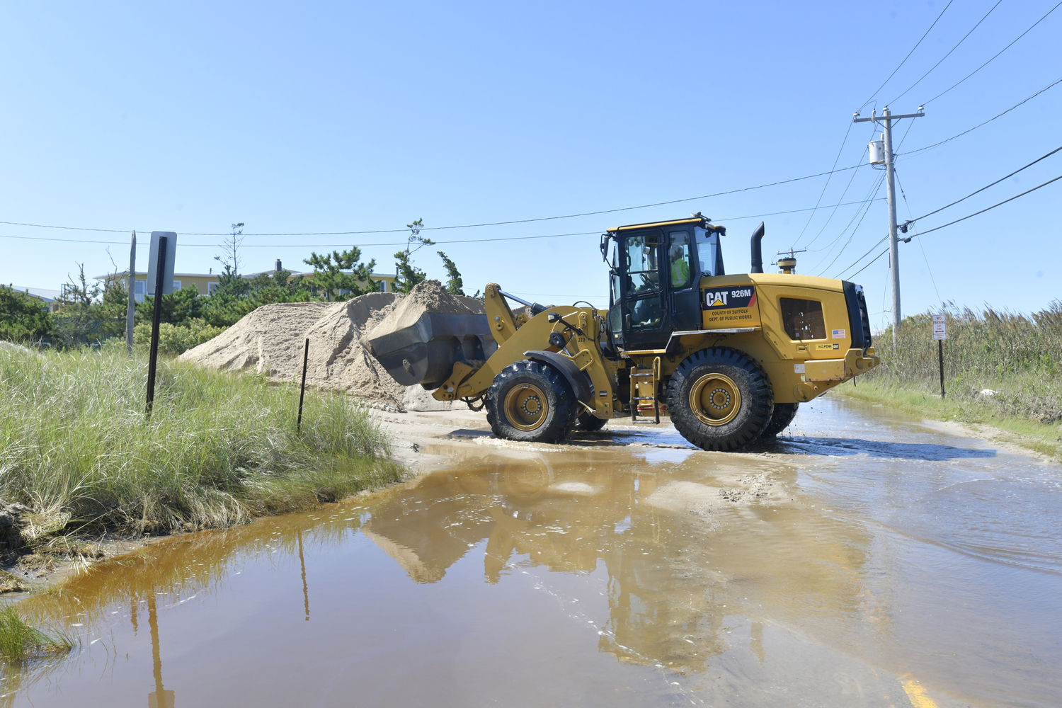 Crews work on removing sand from Dune Road, just east of Sandbar Beach in East Quogue on Thursday after a breach on Wednesday night.  DANA SHAW