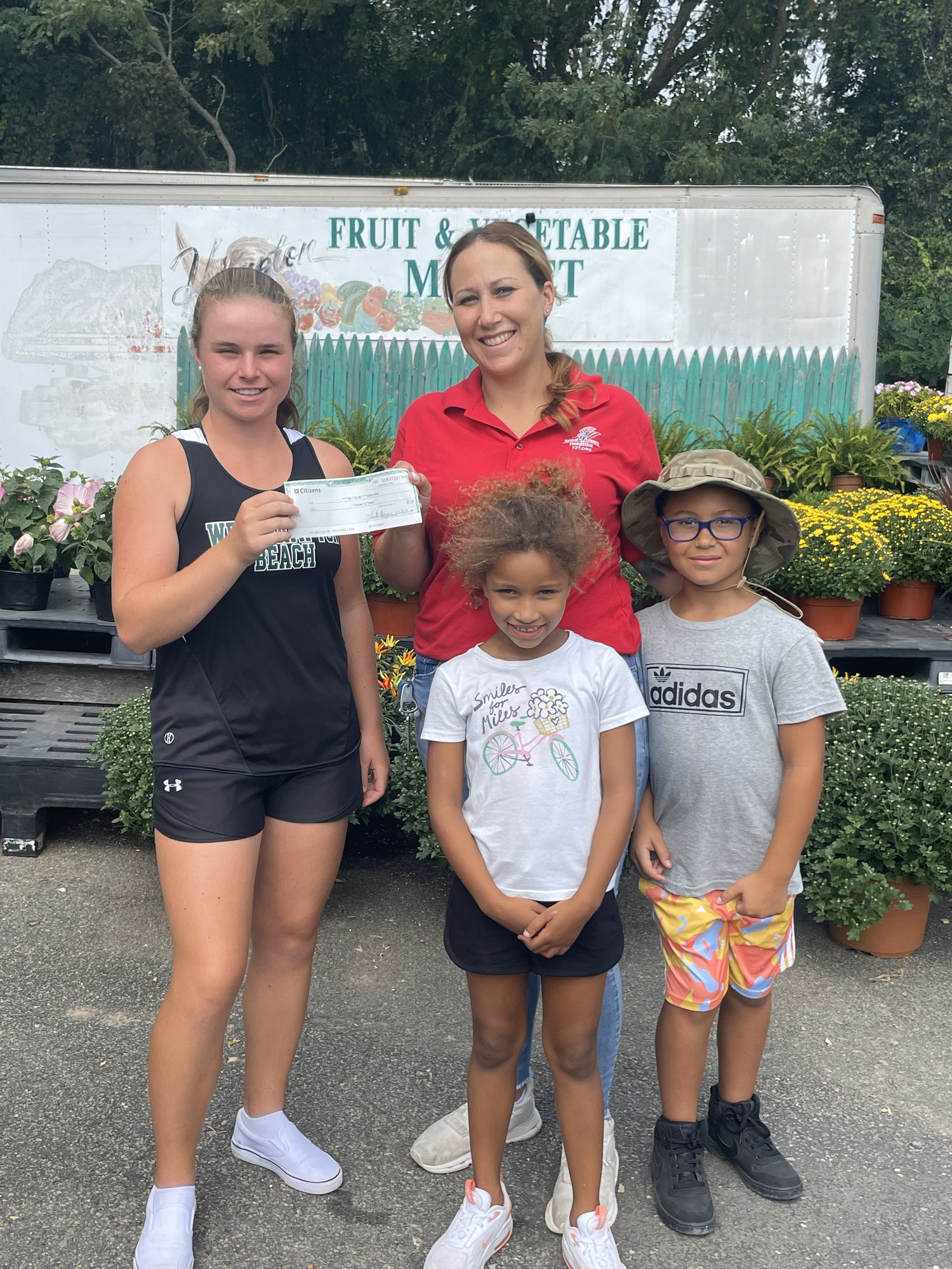 Julia Stabile, left, presents a check to Tunnels to Tower Ambassador Rebecca Briggs and her children, Jayden and Ava. Their husband and father, Technical Sergeant Dashan Briggs, was killed in action in 2018 in Iraq.