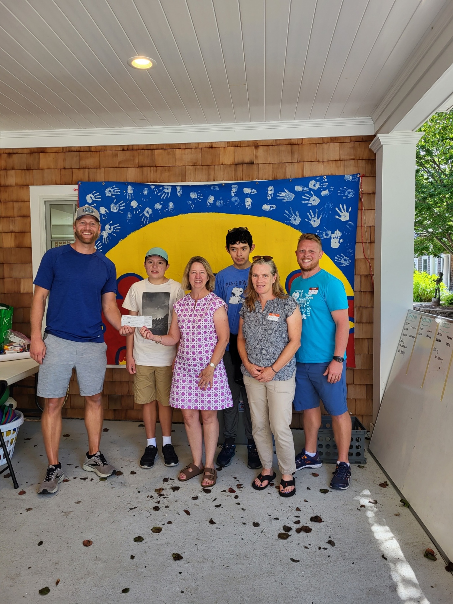 Kiwanis Club of Southampton Town presented a check to the Flying Point Foundation for Autism during its recent camp session at the Southampton Fresh Air Home. The donation represents a portion of the proceeds of the June golf outing organized by Kiwanis. From left, Flying Point Foundation for Autism board member Nick Epley, a camper, Kiwanis President Lorri Schneider, a camper, Kiwanis member Amy Graham, and Camp Flying Point Director Nate Unwin. While at the camp, Kiwanis Club treated campers to ice cream. COURTESY SOUTHAMPTON TOWN KIWANIS